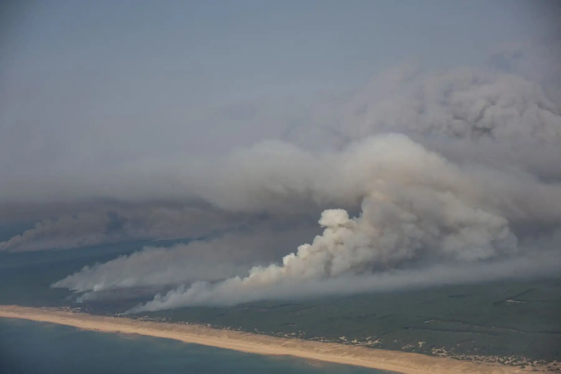 Esta fotografía aérea muestra el humo que emana del incendio forestal al norte de la cuenca de Arcachon, cubriendo el bosque, con una vista de una playa y el océano Atlántico cerca de Lege-Cap-Ferret, en el suroeste de Francia, el 24 de julio de 2026. Foto: AFP