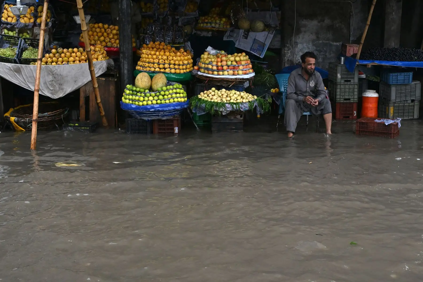 Un vendedor de fruta se encuentra sentado en su puesto de venta en una calle inundada tras las fuertes lluvias en Lahore, Pakistán, el 25 de julio de 2026. Foto: AFP