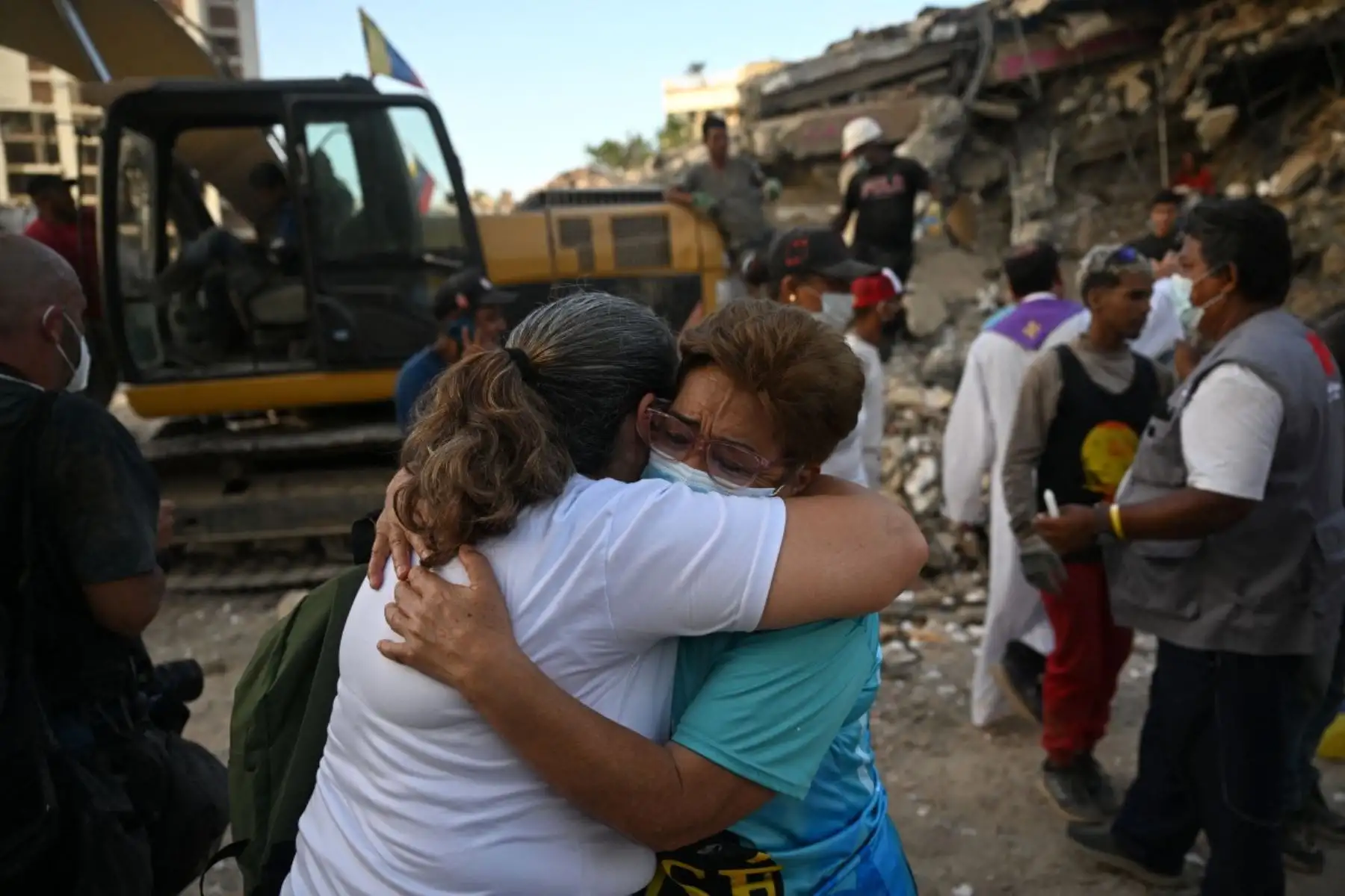 Familiares de las víctimas de los terremotos se abrazan junto a los escombros de un edificio de Obras del Poder Popular (OPP) en Caraballeda, Venezuela. Foto: AFP