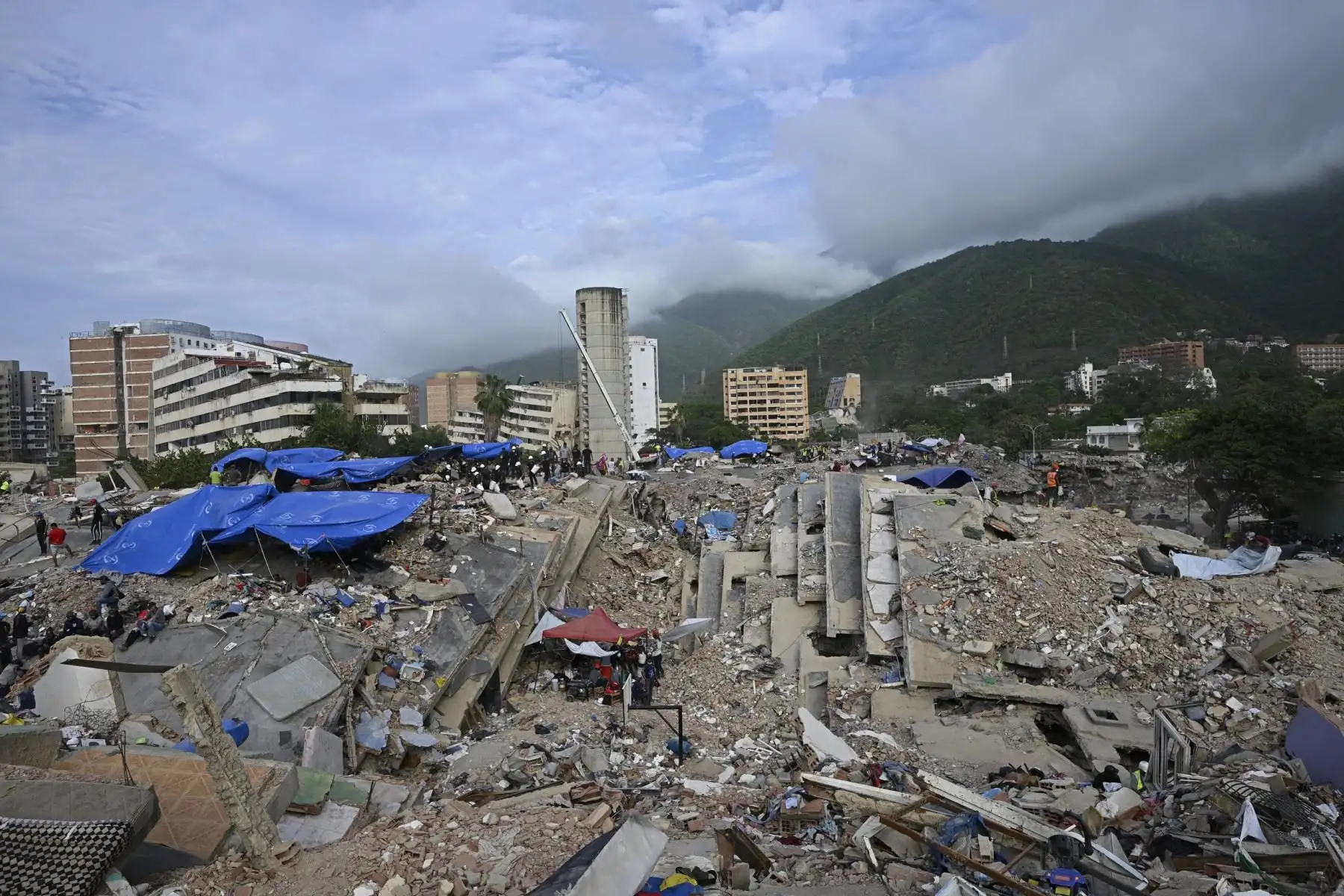Voluntarios y equipos de rescate buscan cuerpos entre los escombros de un edificio derrumbado en Caraballeda, Venezuela, a un mes de los terremotos del 24 de junio. Foto: AFP