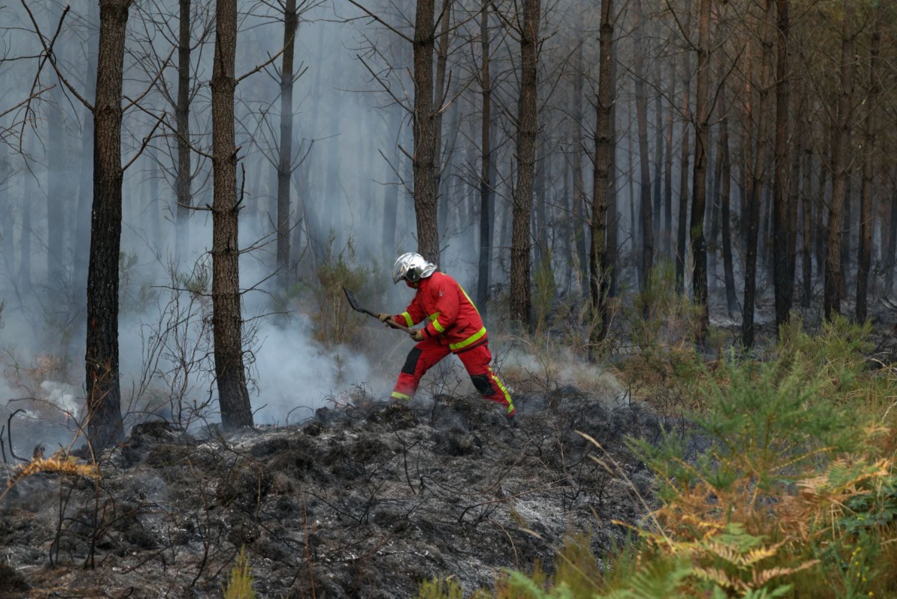 Un bombero del Cuerpo de Bomberos de París golpea con una pala restos humeantes en Marcheprime, al oeste de Burdeos, Francia, el 26 de julio de 2026, mientras un incendio forestal arrasa el bosque al norte de la cuenca de Arcachon (Gironda) desde el 22 de julio. Foto: AFP