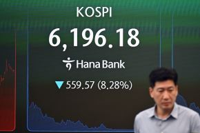 Un operador de divisas pasa frente a una pantalla que muestra el índice bursátil de referencia de Corea del Sur (KOSPI) el 28 de julio de 2026. Foto: AFP
