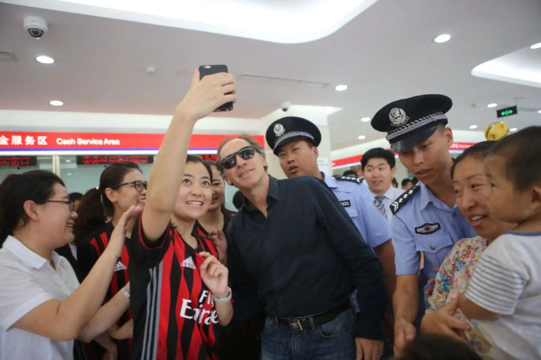 El astro del fútbol italiano Franco Baresi, en el centro, posa con un aficionado chino para una selfie durante un encuentro con fans en una sucursal del Banco de Qingdao en la ciudad de Binzhou, provincia de Shandong, en el este de China. Foto: AFP