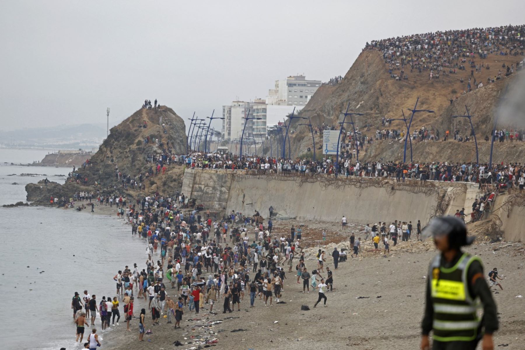 Varias personas se congregan junto a la valla en el lugar de los enfrentamientos cerca de Fnideq, en la frontera entre Marruecos y España. Foto: AFP