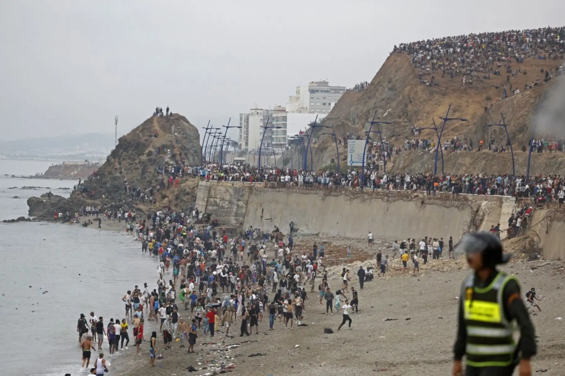 Varias personas se congregan junto a la valla en el lugar de los enfrentamientos cerca de Fnideq, en la frontera entre Marruecos y España. Foto: AFP