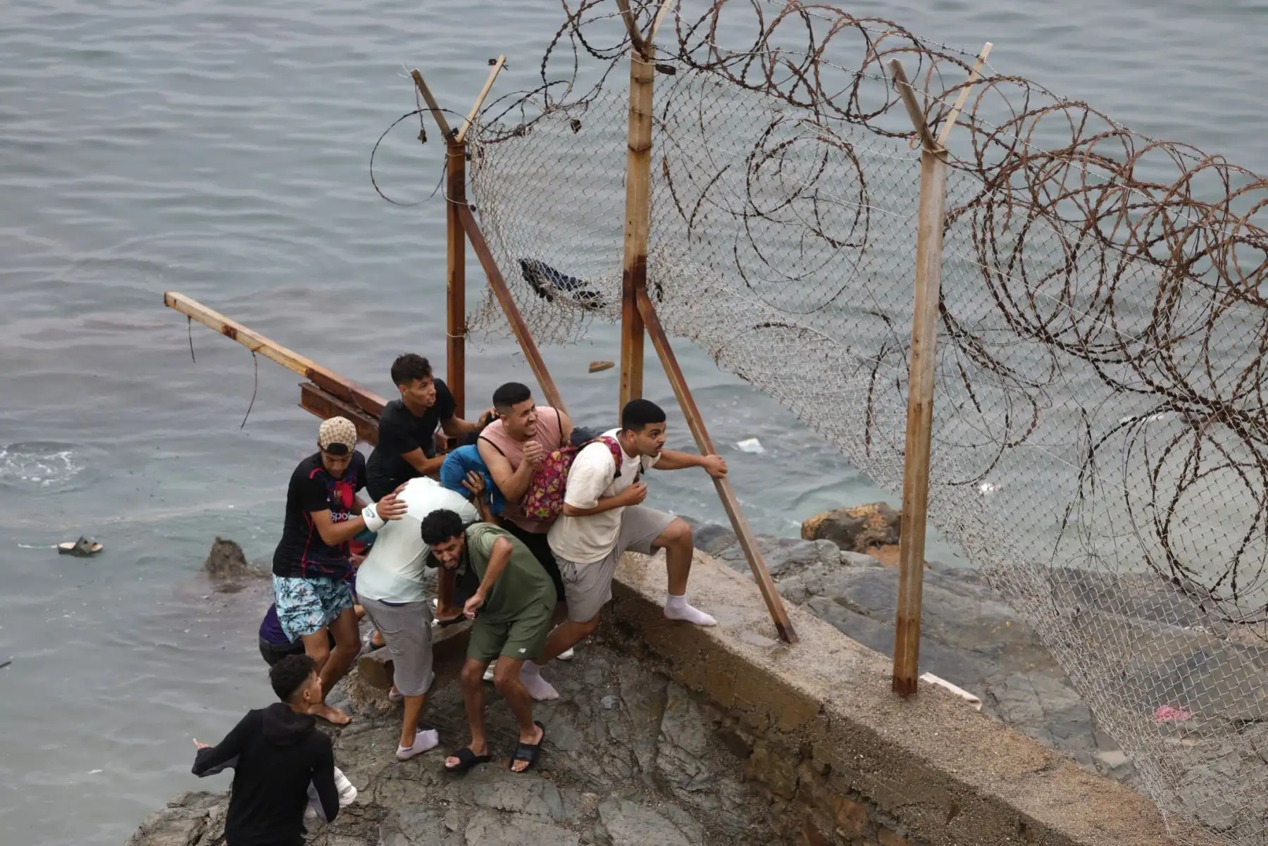 Varias personas se congregan junto a la valla en el lugar de los enfrentamientos cerca de Fnideq, en la frontera entre Marruecos y España. Foto: AFP
