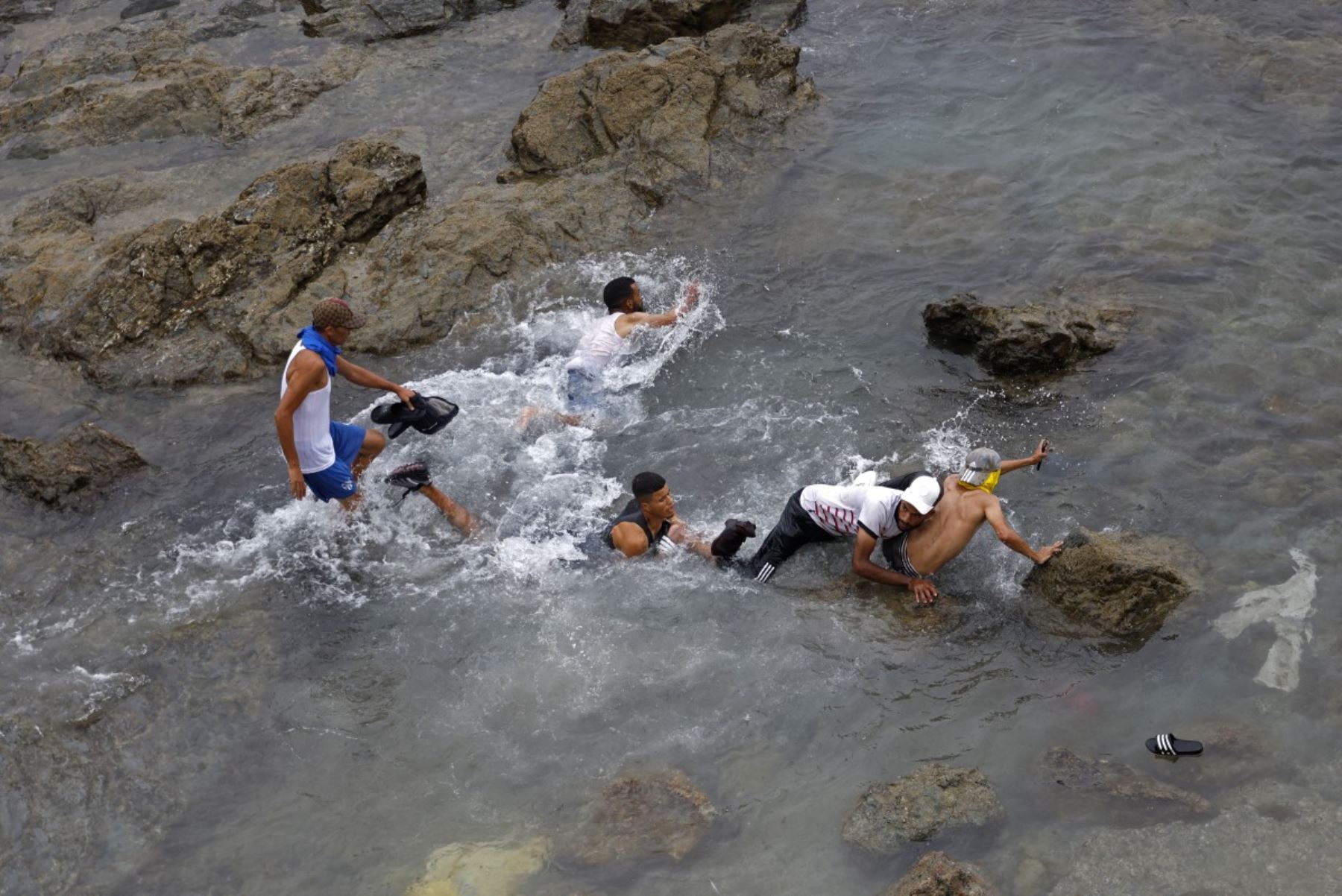 Varias personas intentan nadar en las aguas cercanas a la valla, en las proximidades de Fnideq, en la frontera entre Marruecos y España. Foto: AFP