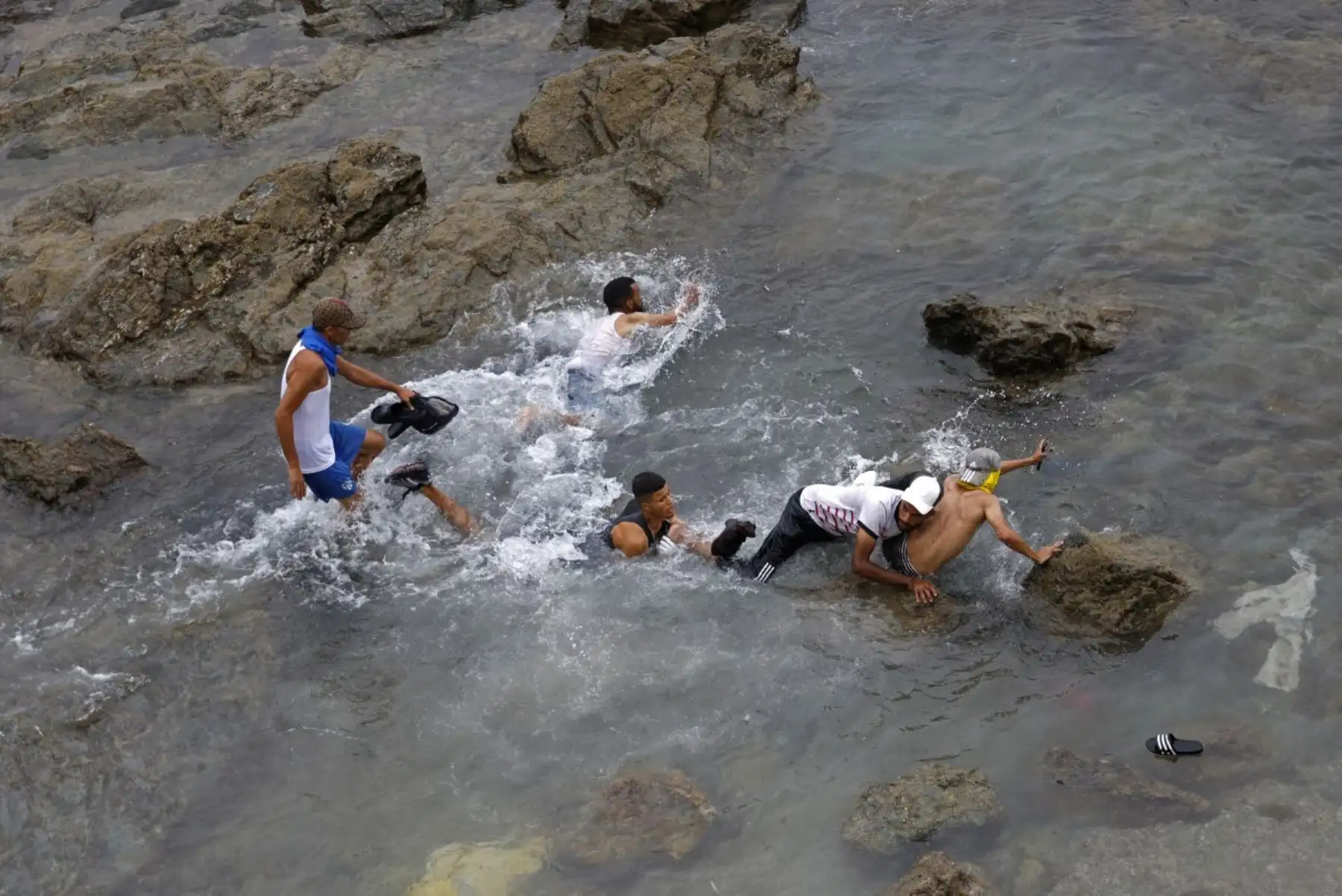 Varias personas intentan nadar en las aguas cercanas a la valla, en las proximidades de Fnideq, en la frontera entre Marruecos y España. Foto: AFP