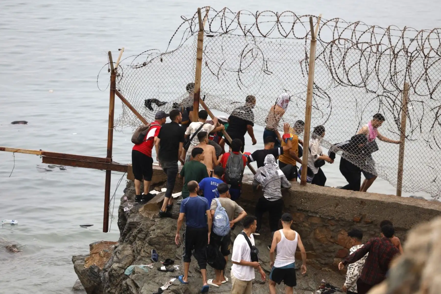 Varias personas se congregan junto a la valla cerca del lugar de los enfrentamientos cerca de Fnideq, en la frontera entre Marruecos y España. Foto: AFP