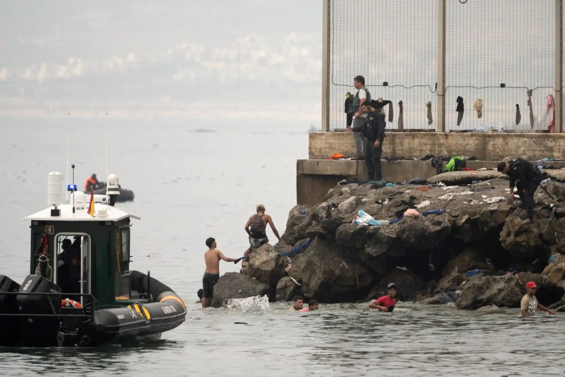 Agentes de la Guardia Civil española controlan a migrantes que intentan cruzar a nado las aguas cercanas a la frontera con Marruecos para entrar en el enclave español de Ceuta, en el norte de África, el 31 de julio de 2026. Foto: AFP