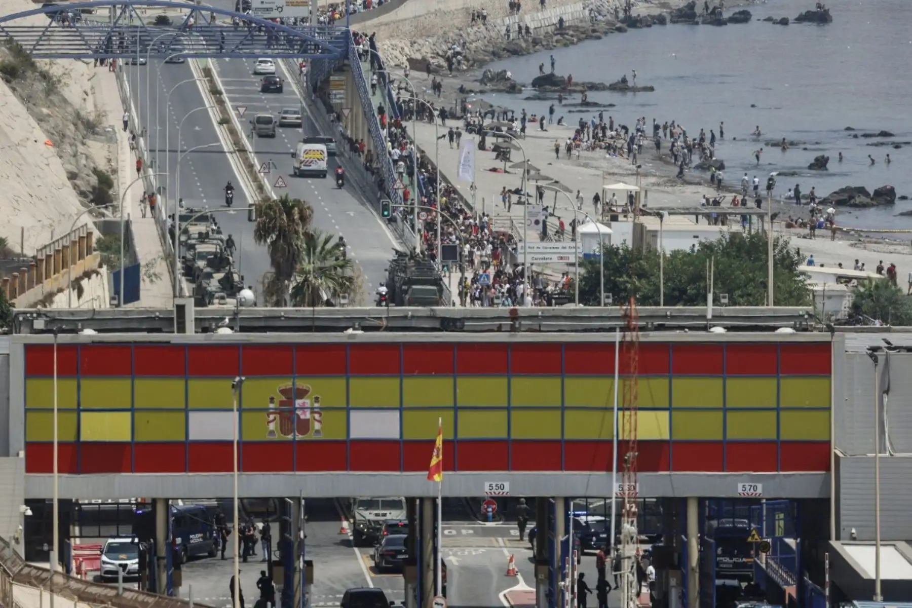 Una fotografía tomada en las afueras de la ciudad marroquí de Fnideq, en la frontera entre Marruecos y España, muestra a migrantes caminando por la costa de Ceuta tras cruzar al enclave español, el 31 de julio de 2026. Foto: AFP