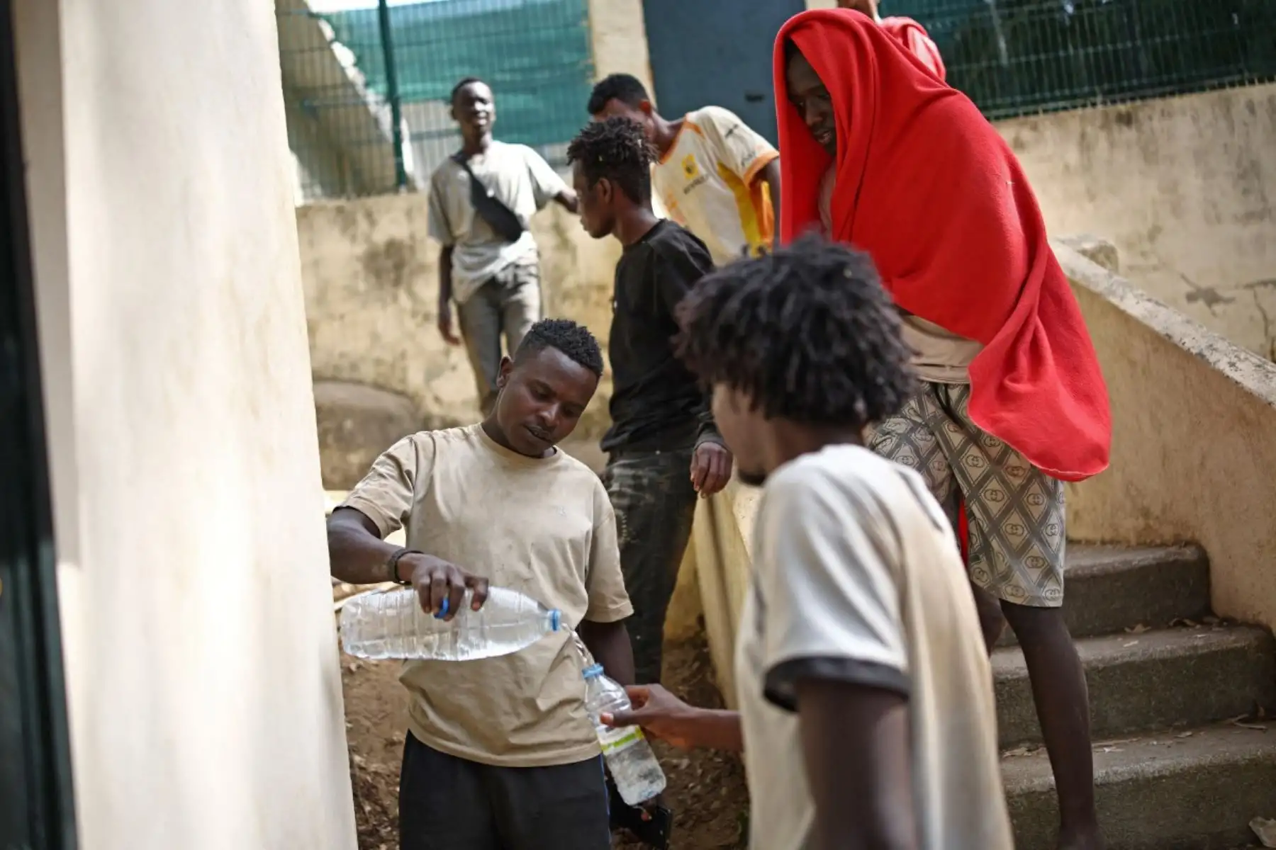 Migrantes recogen agua a las afueras del centro de acogida temporal CETI en el enclave español de Ceuta, en el norte de África, el 1 de agosto de 2026. Foto: AFP
