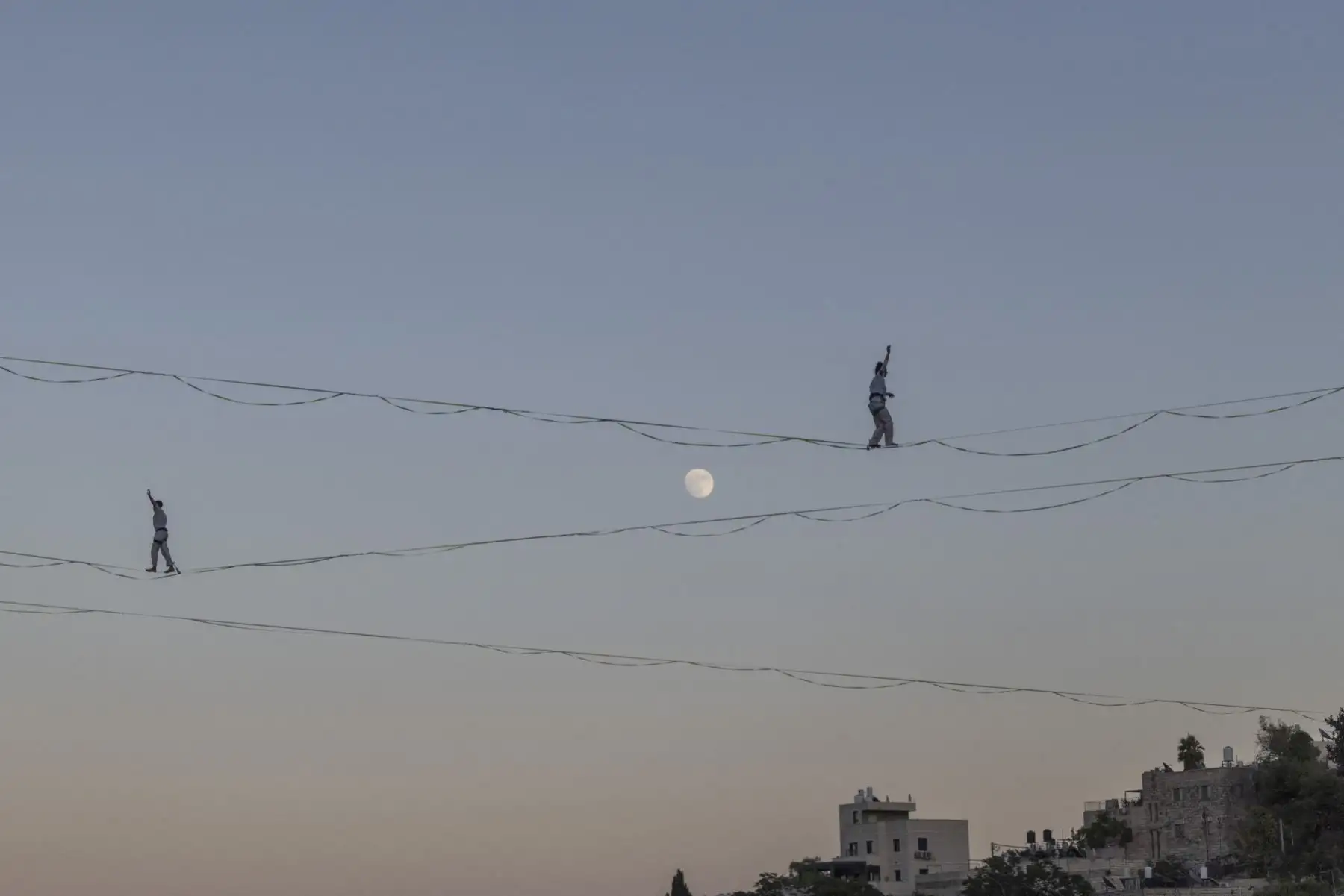 Artistas de la cuerda floja recorren cables suspendidos sobre el valle de Hinnom durante un ensayo general previo a la inauguración del 65.º Festival de Israel, que se celebrará en la frontera entre Jerusalén Este y Oeste, el 27 de julio de 2026, en Jerusalén. Foto: AFP