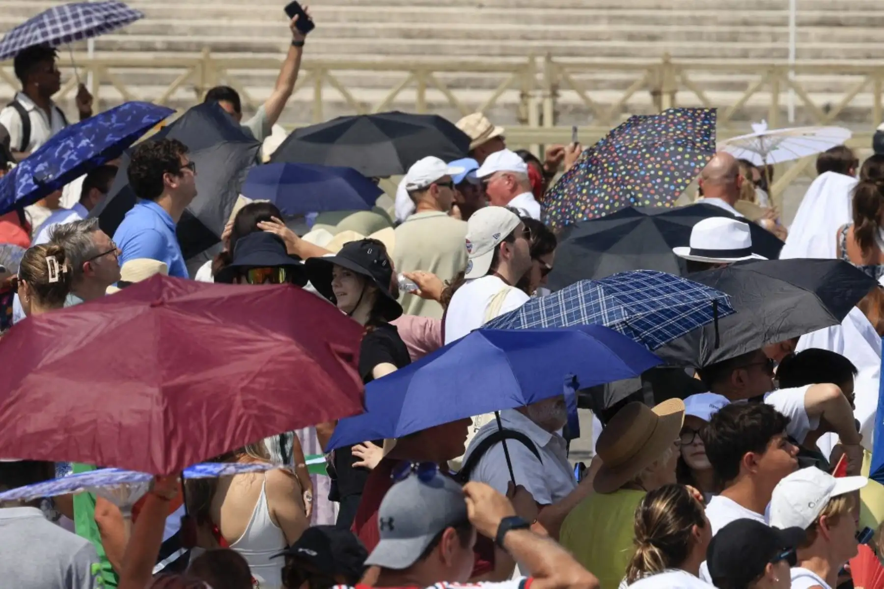 Fieles se resguardan del intenso sol mientras esperan el rezo del Ángelus, la oración del mediodía oficiada por el Papa León XIV desde la ventana de su estudio con vistas a la Plaza de San Pedro en el Vaticano, el 2 de agosto de 2026. En su discurso en español, el Papa expresó su preocupación por la alarmante situación en Ceuta, la ciudad autónoma española en la costa norte de África, donde en los últimos días decenas de miles de personas han intentado cruzar por mar desde Marruecos y al menos 67 han fallec