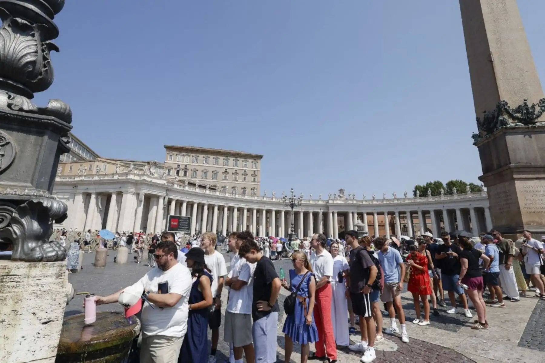 Fieles hacen cola en una fuente de agua para refrescarse del calor mientras esperan el Ángelus, la oración del mediodía celebrada por el Papa León XIV desde la ventana de su estudio con vistas a la Plaza de San Pedro en el Vaticano, el 2 de agosto de 2026. Foto: AFP