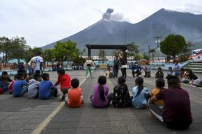 Niños se reúnen en una plaza mientras el volcán de Fuego entra en erupción en Alotenango, el 4 de agosto de 2026. Foto: AFP