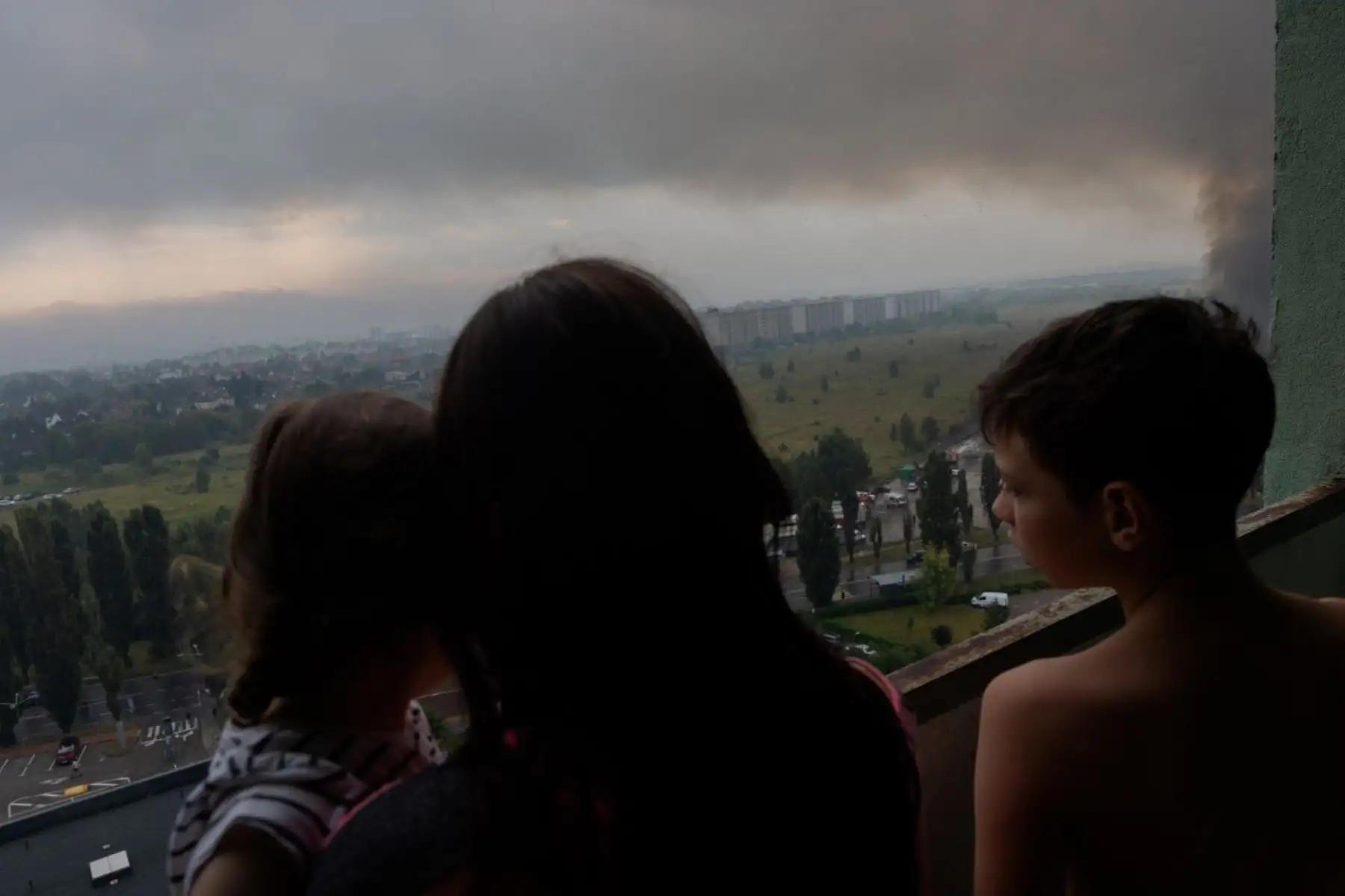 Una familia ucraniana observa desde un balcón el humo que se eleva de un incendio tras los masivos ataques rusos con misiles balísticos y drones en Kiev, en el contexto de la invasión rusa de Ucrania. Los ataques rusos contra la capital ucraniana y la región circundante causaron la muerte de al menos dos personas y dejaron decenas de heridos, tras nuevos ataques nocturnos con misiles y drones. Foto: ANDINA/AFP