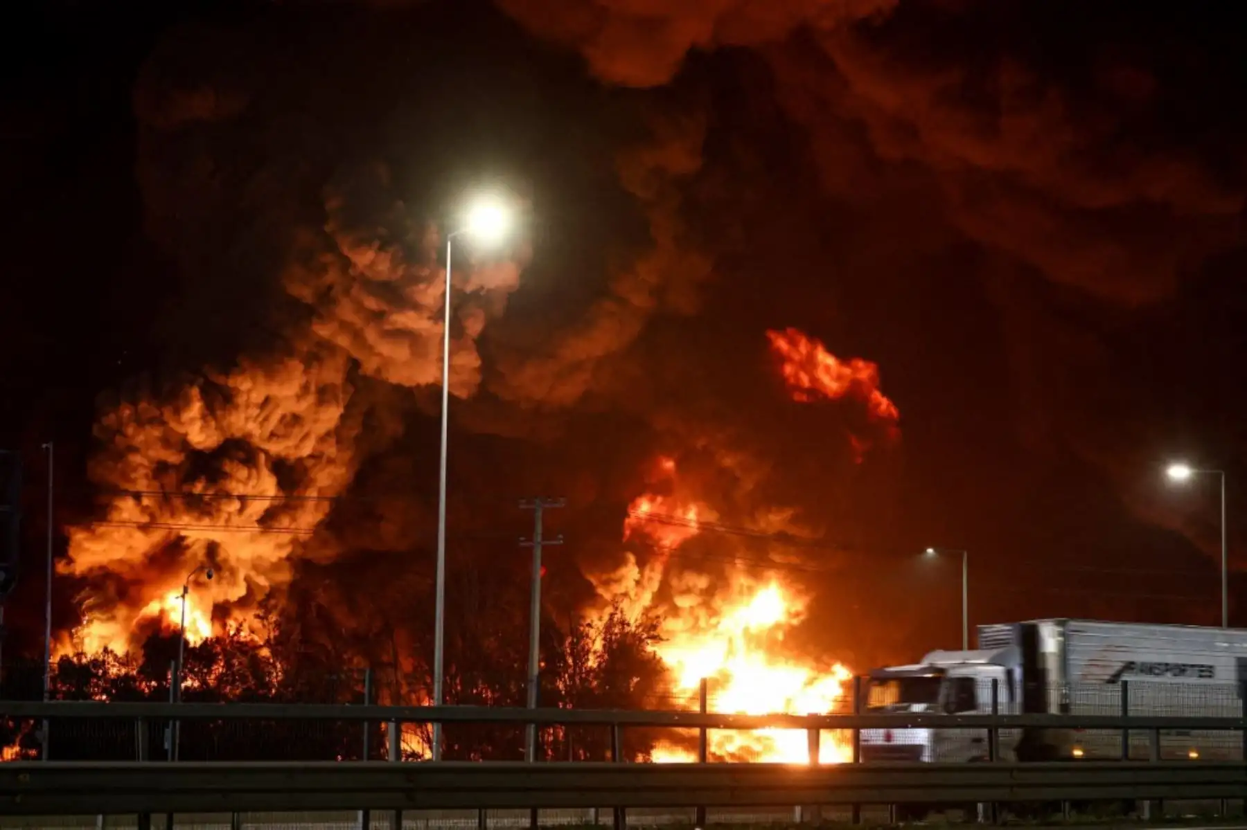 Un camión de carga circula por la carretera mientras se desata un incendio en una planta química de Santiago, Chile.  Foto: AFP