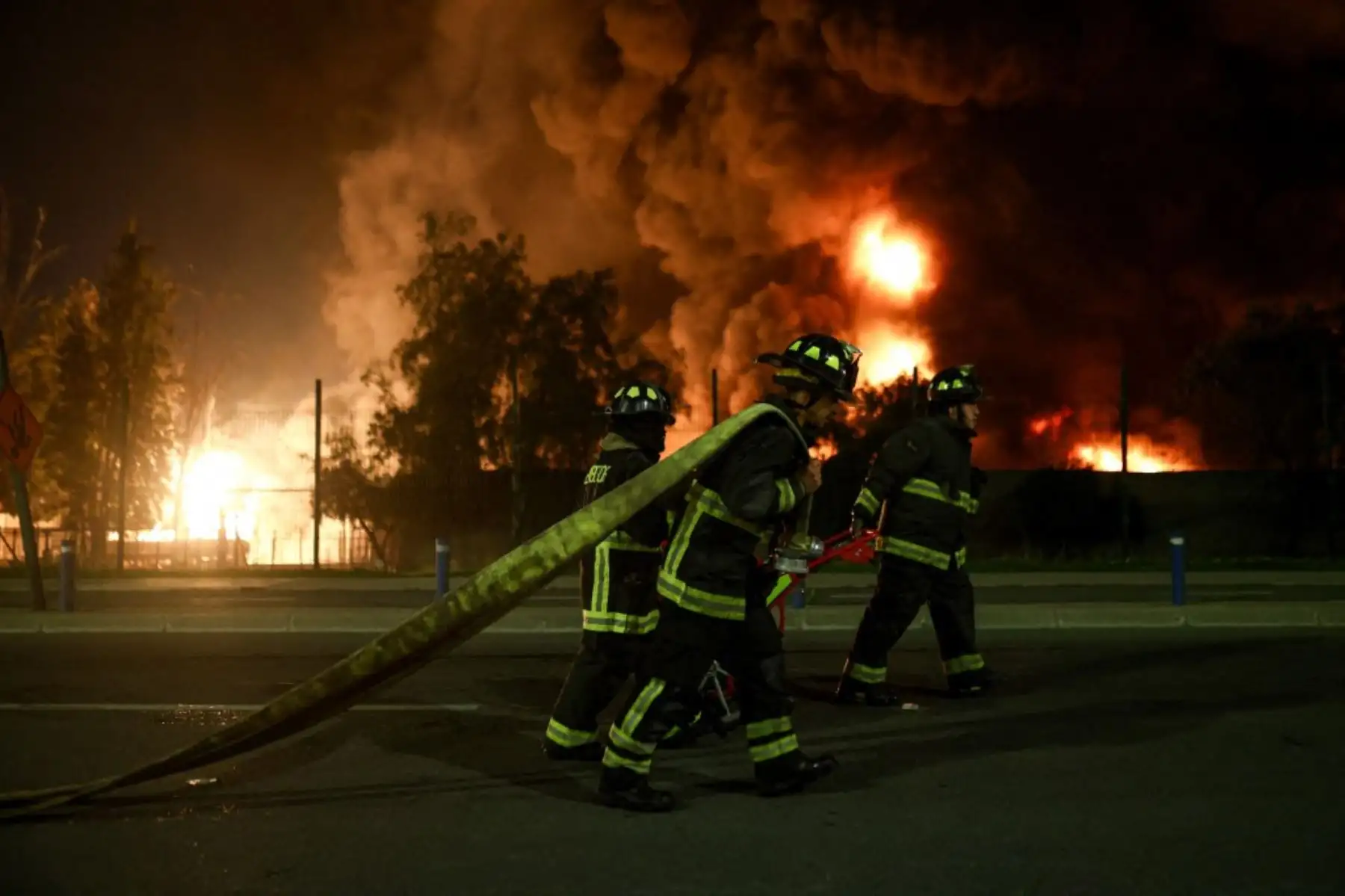 Bomberos trabajan para extinguir un gran incendio desatado en una planta química, mientras llamas y humo se elevan en Santiago, Chile. AFP