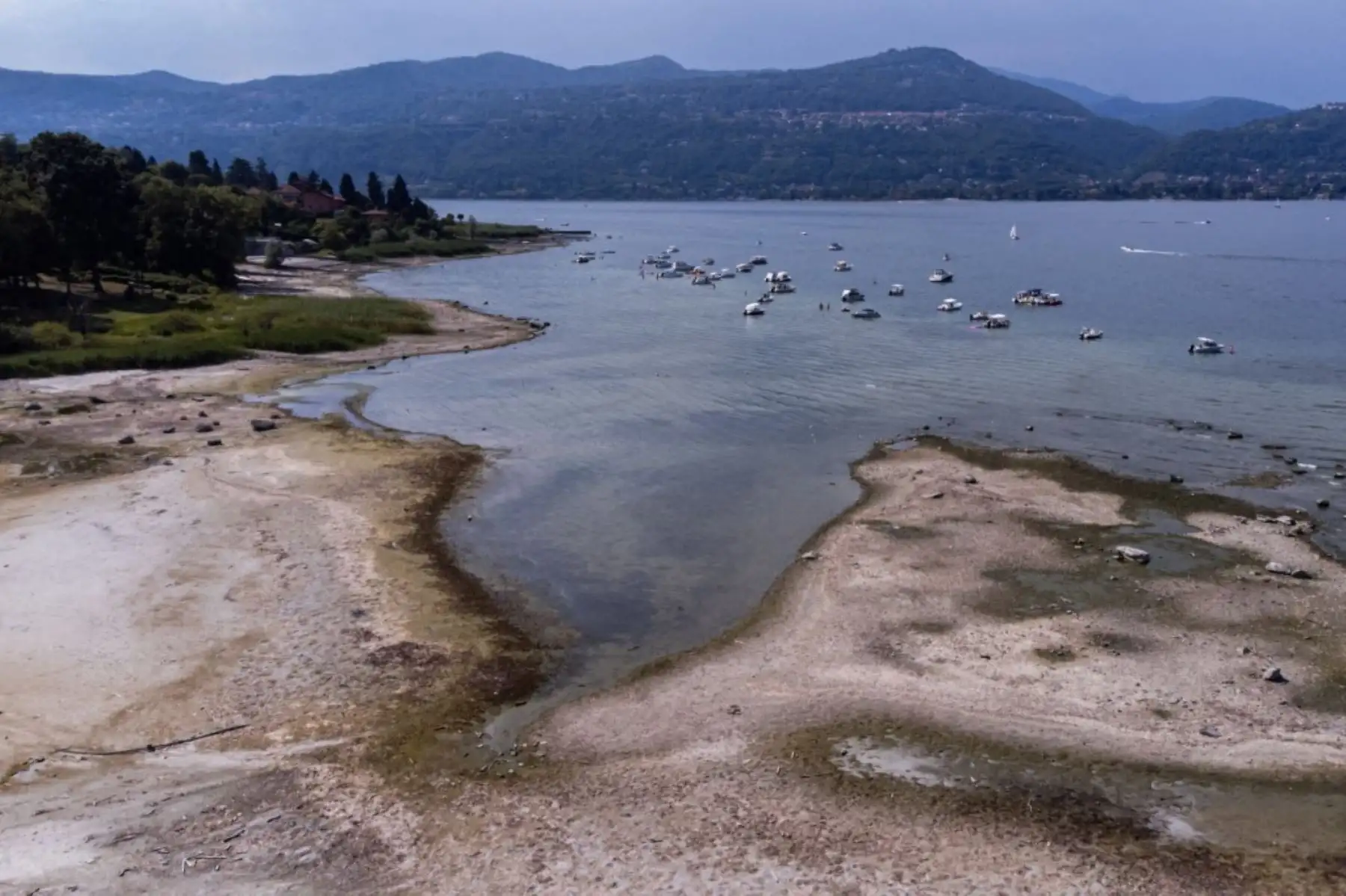 Vista aérea de una extensa franja de orilla expuesta y niveles de agua bajos en el lago Maggiore, en el norte de Italia. La sequía prolongada y el calor extremo han llevado al lago a su nivel más bajo en casi nueve décadas, afectando la navegación. AFP
