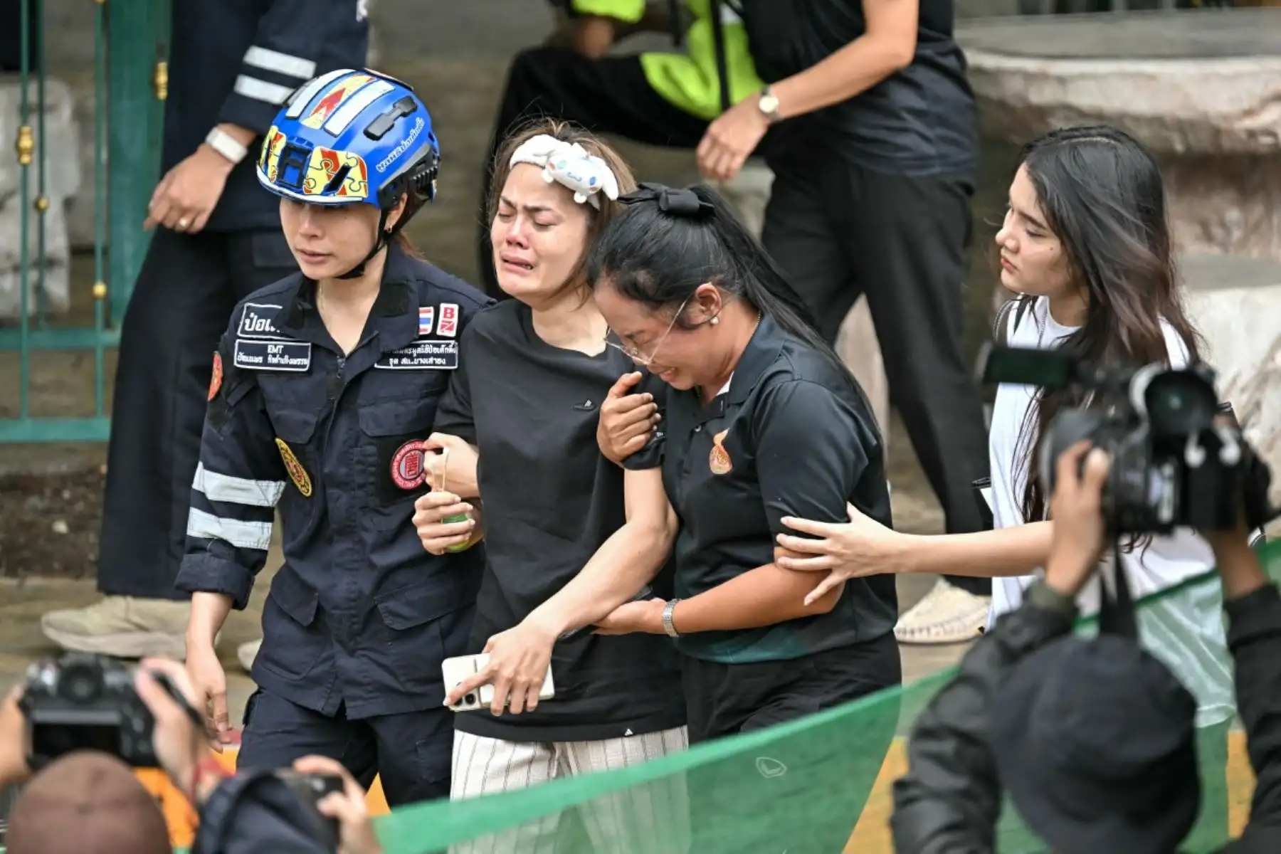 Familiares de un maestro fallecido en un tiroteo escolar son conducidos hacia una ambulancia en el distrito de Bang Kruai, provincia de Nonthaburi, al norte de Bangkok, la capital de Tailandia. AFP