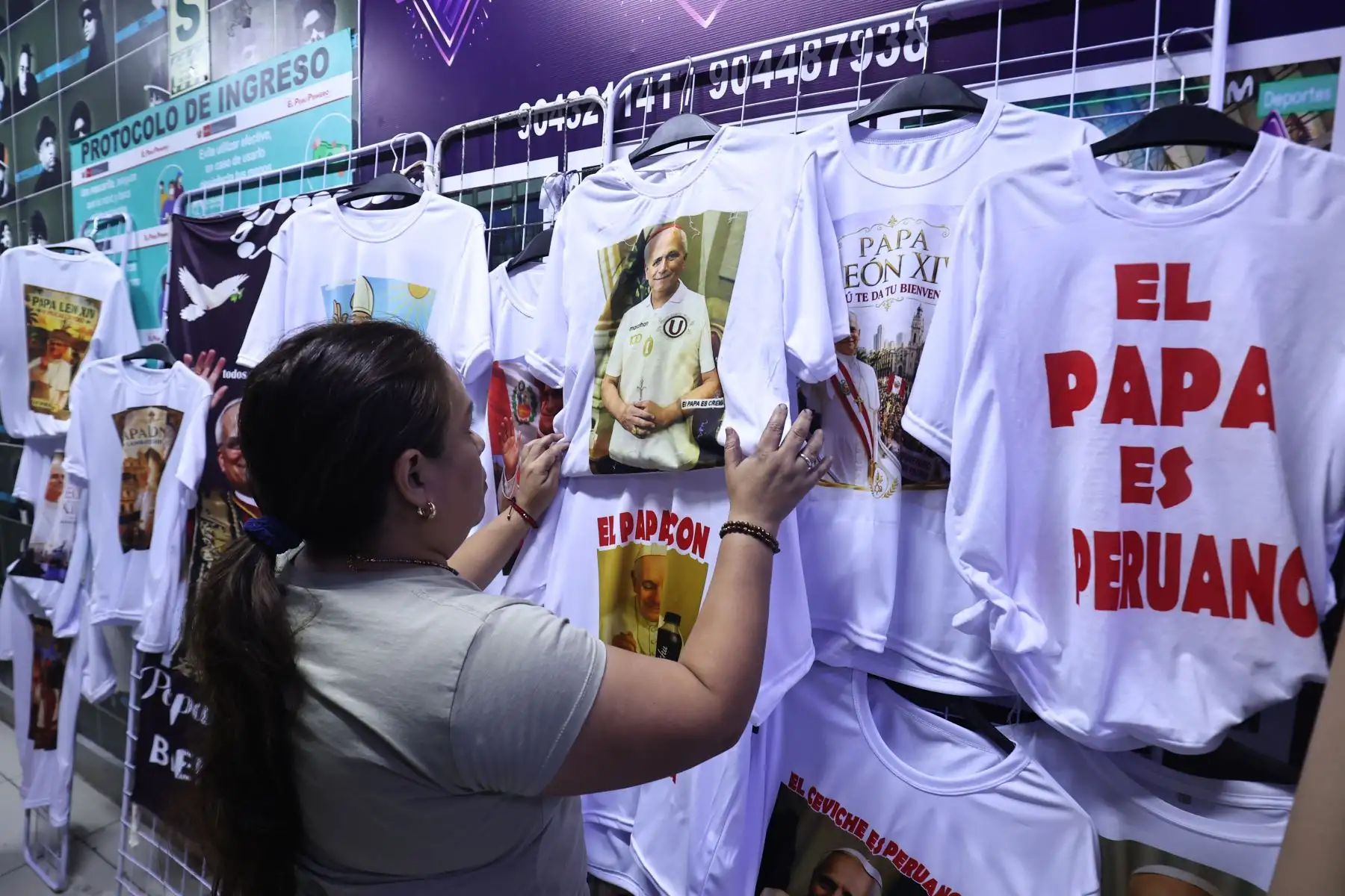 Victoria Quiñonez, confeccionista del polo del papa León XIV en el emporio de Gamarra muestra todos los modelos disponibles además de vinchas y banderolas.

Foto:ANDINA / Juan Carlos Guzmán Negrini