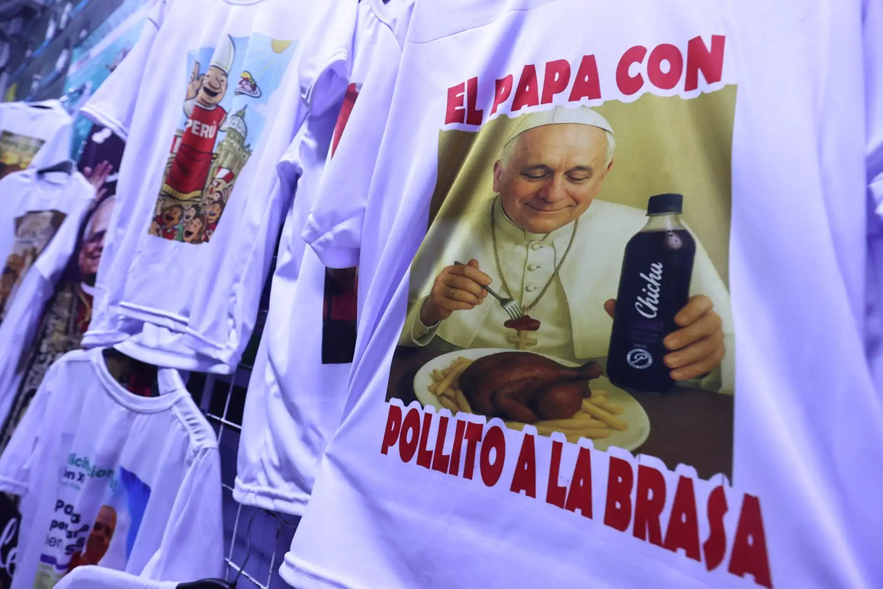 Victoria Quiñonez, confeccionista del polo del papa León XIV en el emporio de Gamarra muestra todos los modelos disponibles además de vinchas y banderolas.

Foto:ANDINA / Juan Carlos Guzmán Negrini