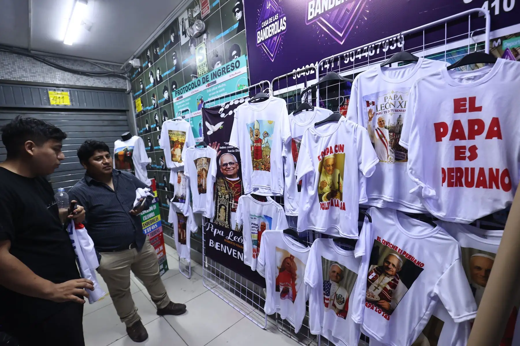 Victoria Quiñonez, confeccionista del polo del papa León XIV en el emporio de Gamarra muestra todos los modelos disponibles además de vinchas y banderolas.

Foto:ANDINA / Juan Carlos Guzmán Negrini