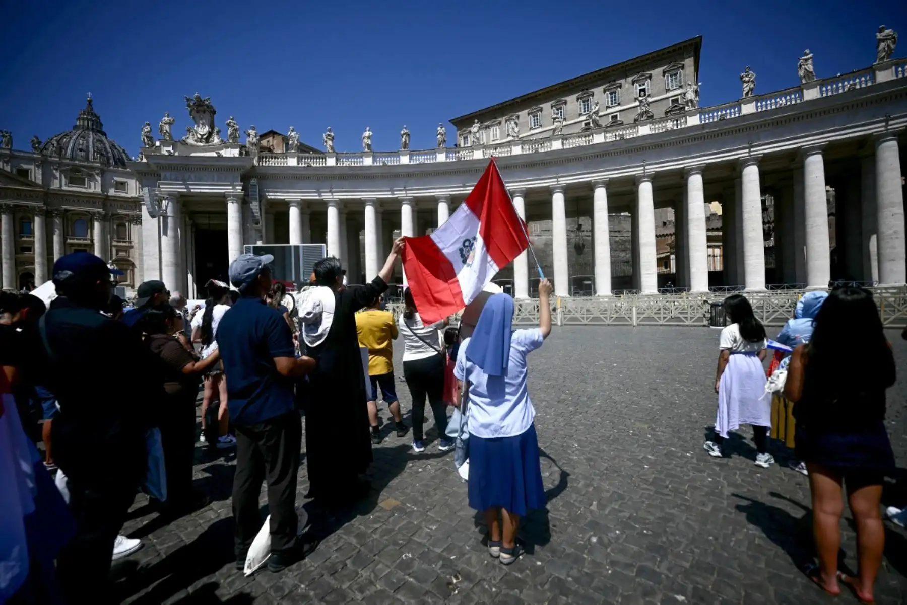 Una monja ondea una bandera nacional peruana mientras permanece junto a otros fieles durante la oración del Ángelus del Papa León XIV en la Plaza de San Pedro, en el Vaticano. Foto: ANDINA/AFP