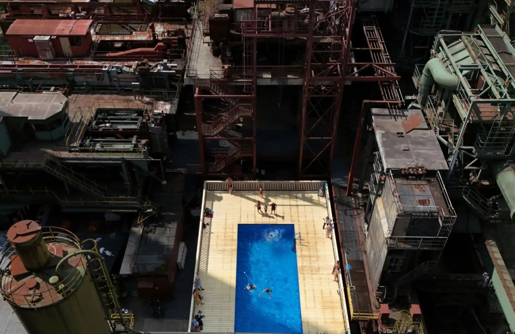Una vista aérea tomada el 5 de agosto de 2026 muestra a los visitantes disfrutando del agua de la piscina "Werksschwimmbad" en Zeche Zollverein, en Essen, al oeste de Alemania. Foto: AFP