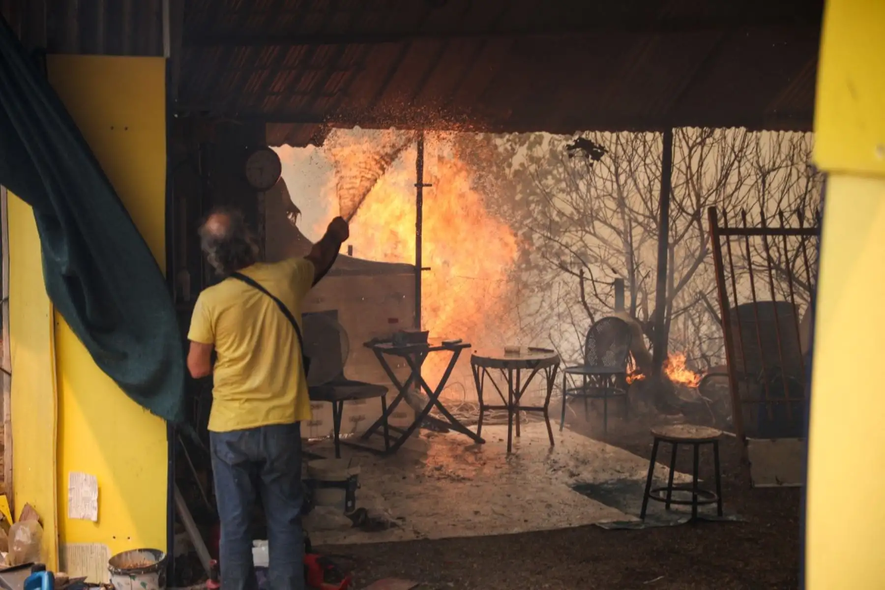 Un residente local intenta extinguir el incendio que se ha declarado en su casa en la región de Megara, al oeste de Atenas, el 2 de agosto de 2026. Grecia se enfrentó el 2 de agosto de 2026 a múltiples frentes y a un creciente número de daños tras una semana de incendios forestales que devastaron más de 12.000 hectáreas de bosques y tierras agrícolas, según los expertos. Foto: AFP