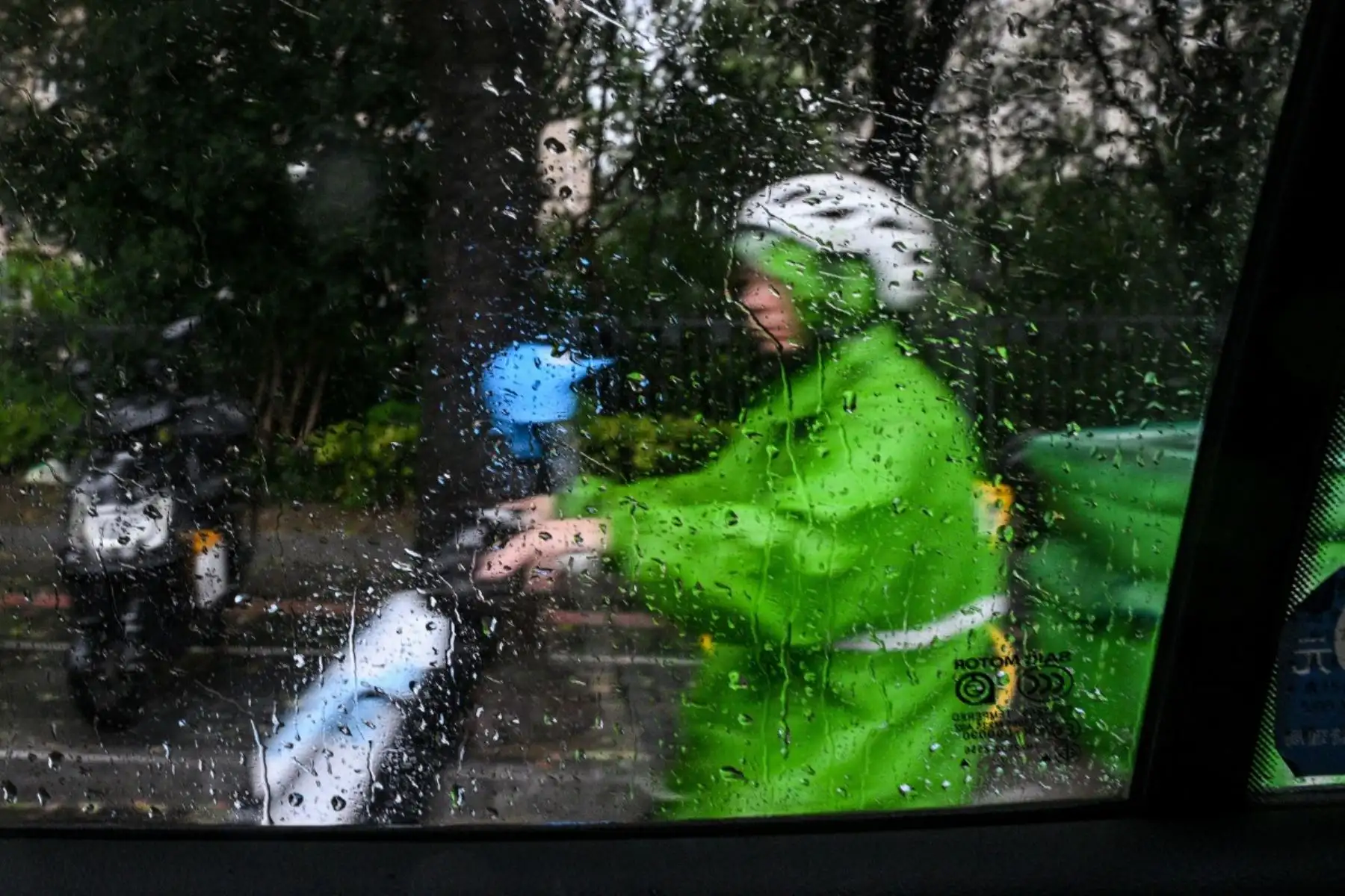 Un hombre en un escúter a través de la lluvia en la ventanilla de un taxi, un día después de que el tifón Dolphin tocara tierra en Shanghái. Foto: AFP