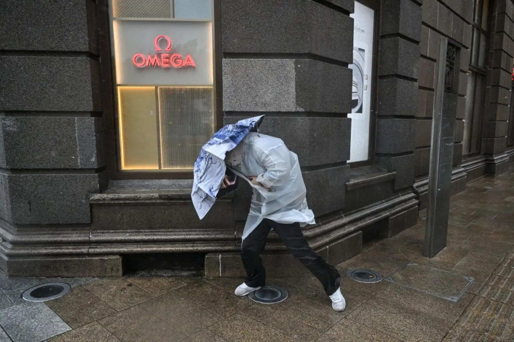 Una persona utiliza un paraguas para protegerse de la lluvia y el viento en el Bund, un día después de que el tifón Dolphin tocara tierra en Shanghái. Foto: AFP