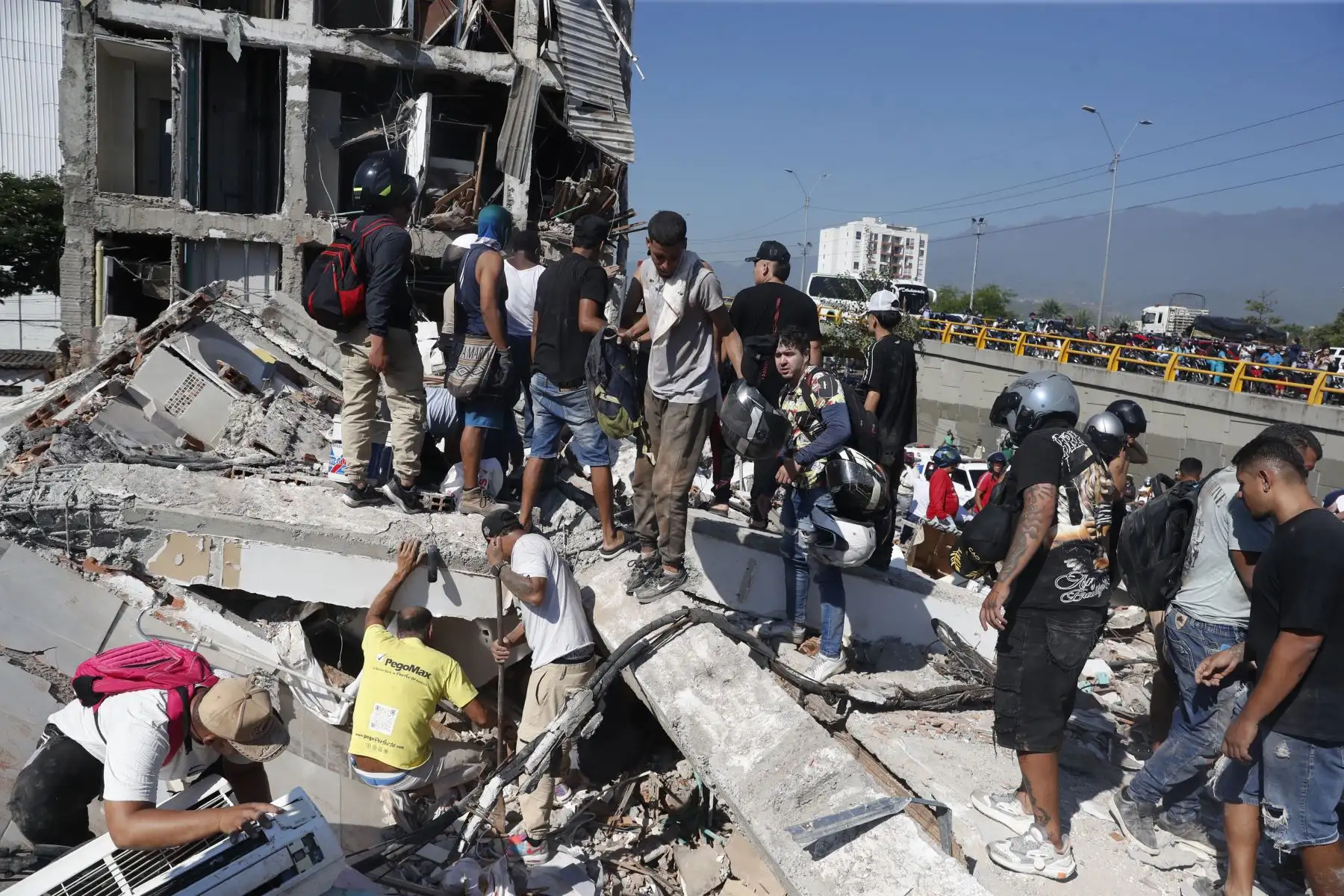 Personas caminan sobre los escombros de un edificio colapsado este lunes, en Cali (Colombia). Al menos 20 edificios sufrieron graves daños por consecuencia del terremoto de magnitud 7,4 que sacudió la mayor parte del país, con epicentro en la zona del Pacífico. Foto: EFE