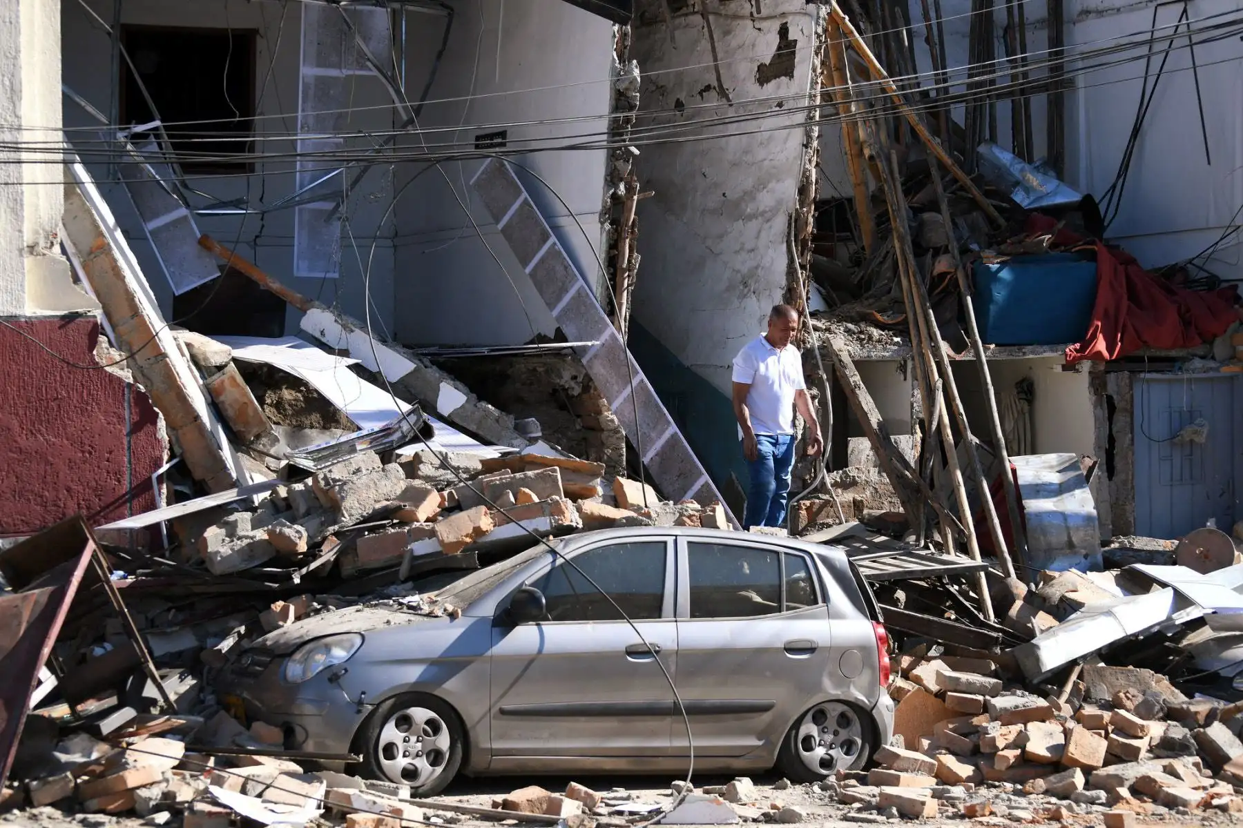 Un hombre permanece junto a un automóvil y unos edificios dañados tras el terremoto en Pereira, Colombia. Equipos médicos acudieron rápidamente a asistir a las víctimas después de que varios edificios sufrieran daños o colapsaran. Foto: AFP