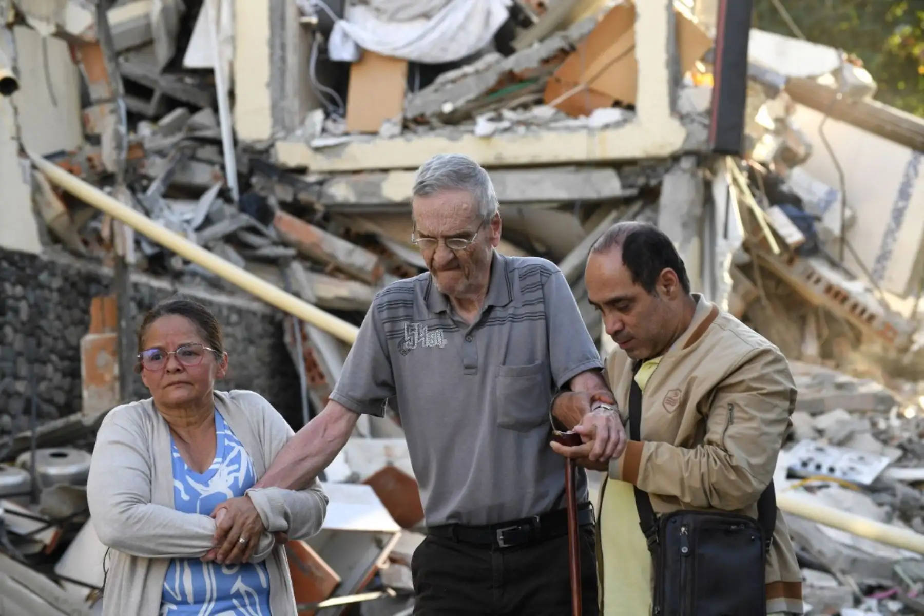 Un anciano recibe ayuda para caminar junto a los escombros de un edificio derrumbado tras el terremoto en Pereira, Colombia. Foto: AFP