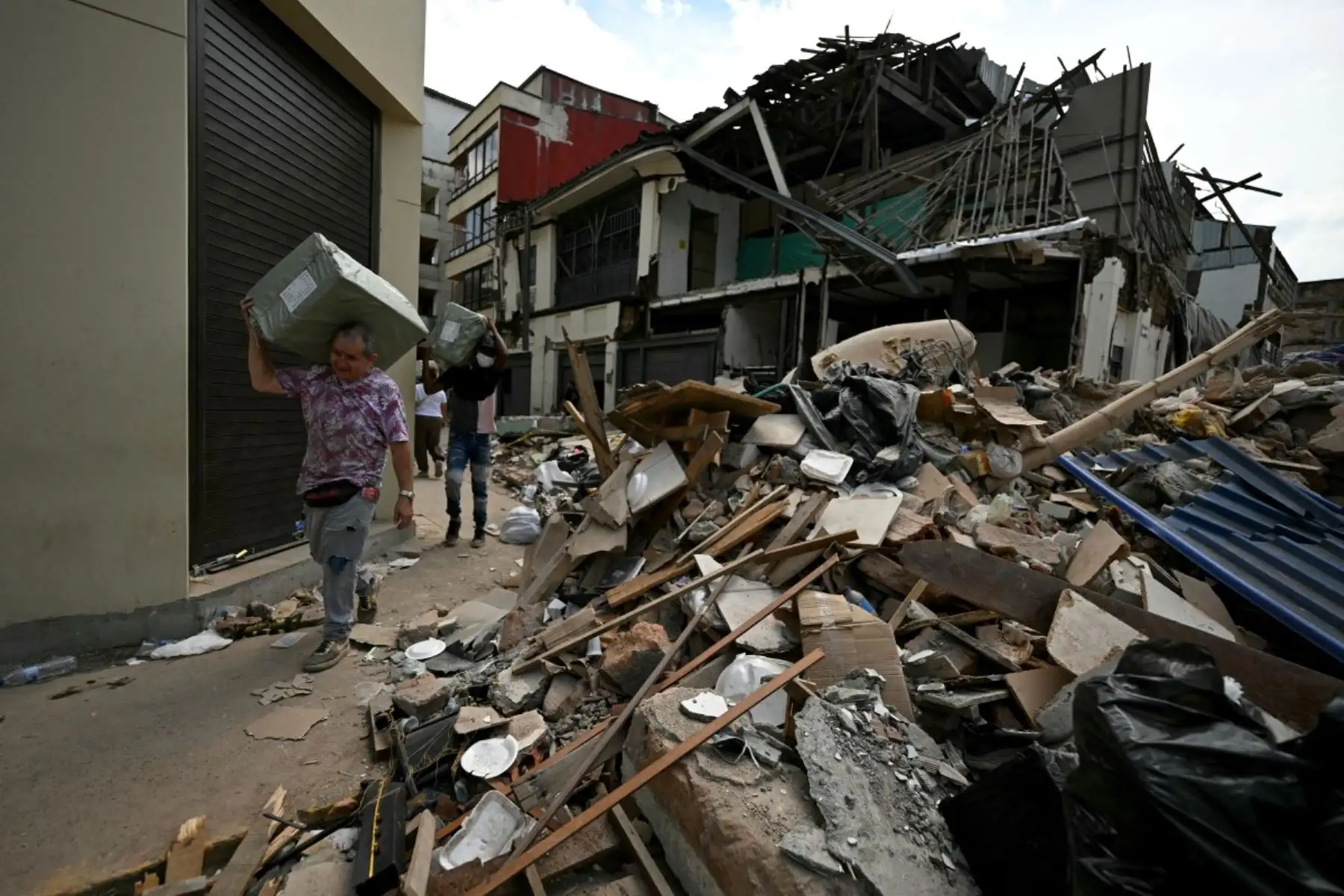 Cuatro días después del terremoto de magnitud 7,4 que sacudió Pereira, Colombia, varias personas transportaron cajas entre los escombros de un edificio derrumbado. Foto: AFP
