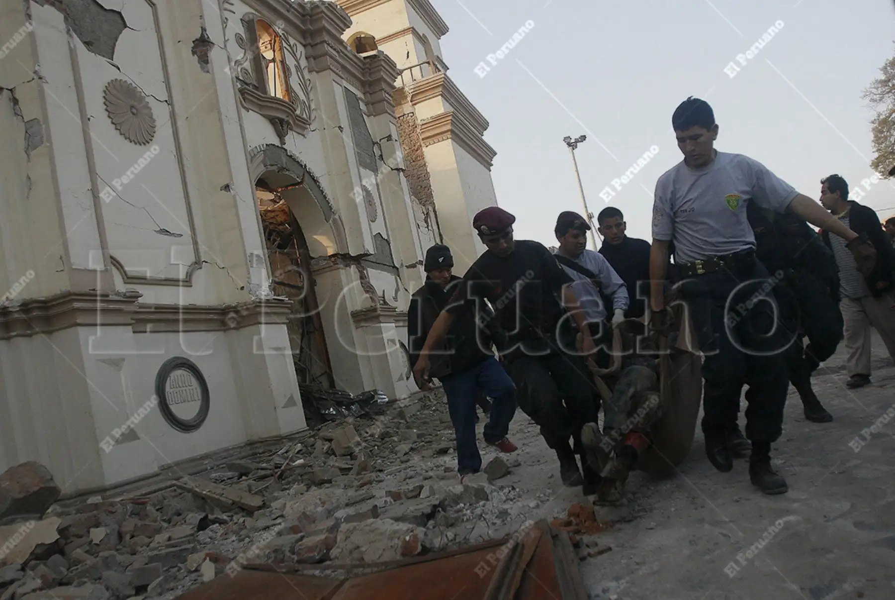 Pisco, Ica – 16 agosto 2007 / Policías de la PNP, trasladan el cuerpos de víctimas a consecuencia del terremoto, pasando por delante de la iglesia San Clemente, que también está bastante afectada en sus estructuras. Foto: Archivo Histórico de El Peruano