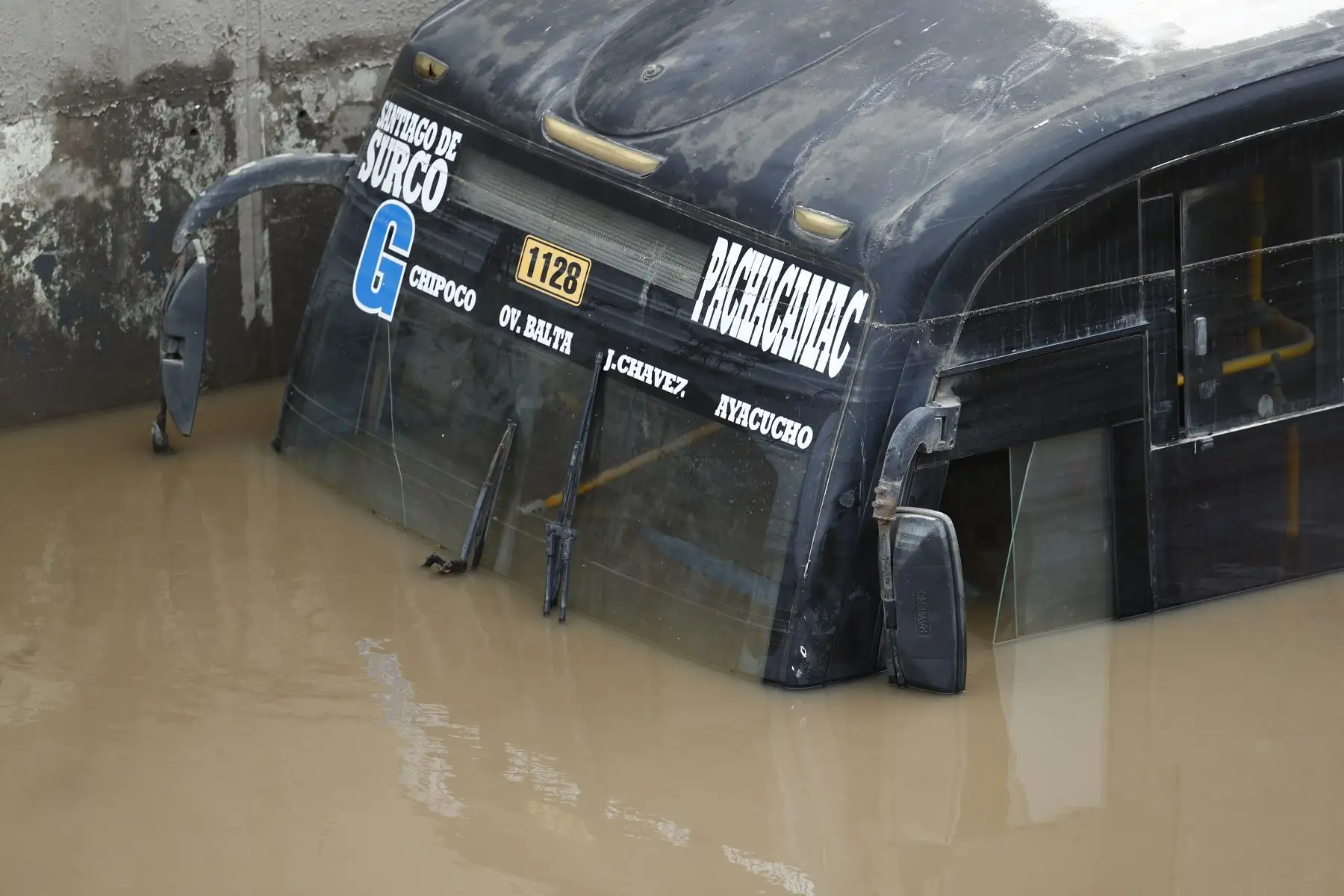 Un bus de transporte público permanece varado en el by pass de la avenida Pachacútec, donde el nivel del agua cubre más de la mitad de la unidad. Foto: ANDINA/Daniel Bracamonte.