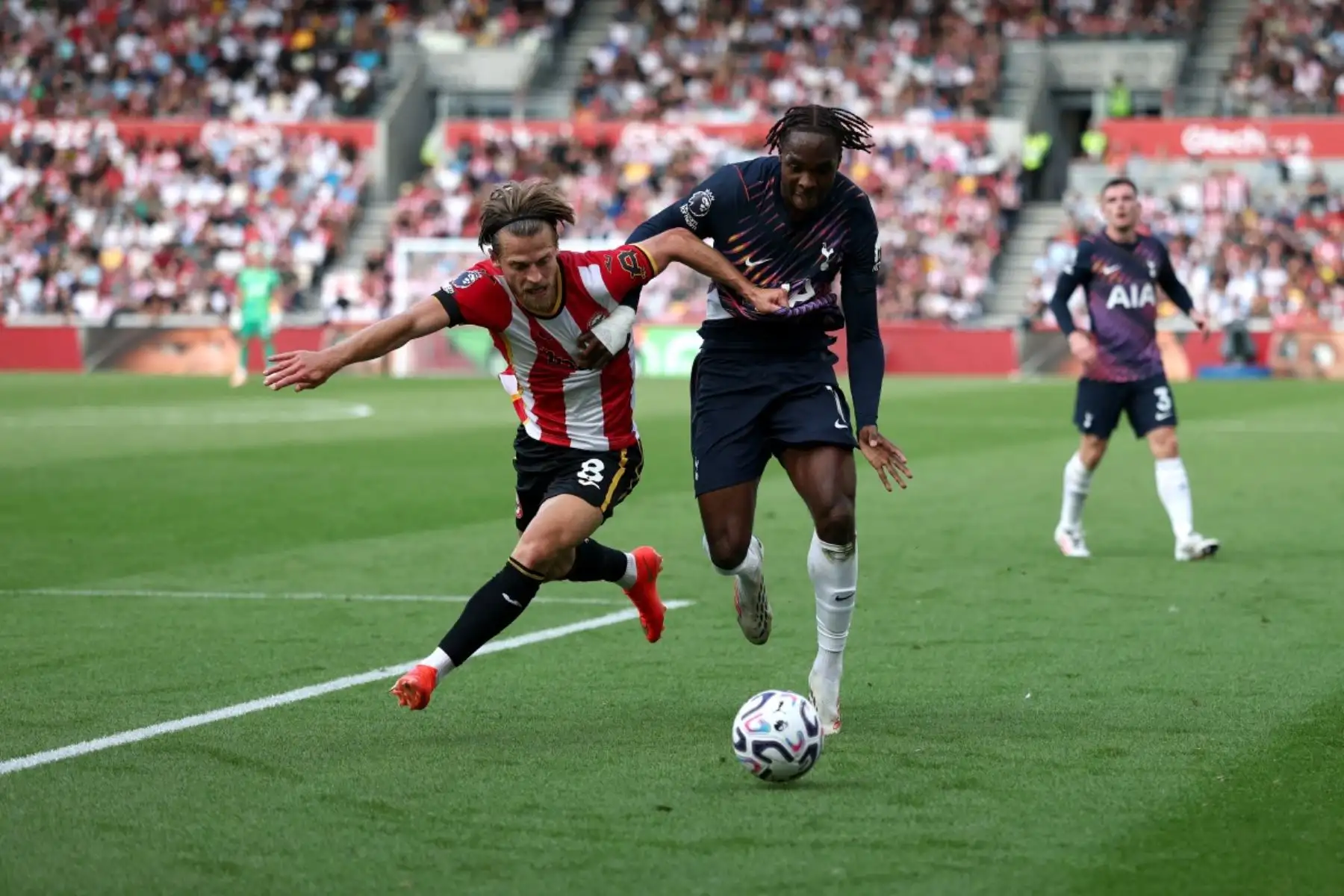 El centrocampista danés del Brentford, Mathias Jensen, número 08, lucha por el balón con el centrocampista holandés del Brentford, Antoni Milambo, número 17, durante el partido de la Premier League inglesa entre el Brentford y el Tottenham Hotspur en el Gtech Community Stadium de Londres el 22 de agosto de 2026. (Foto de Adrian DENNIS / AFP)