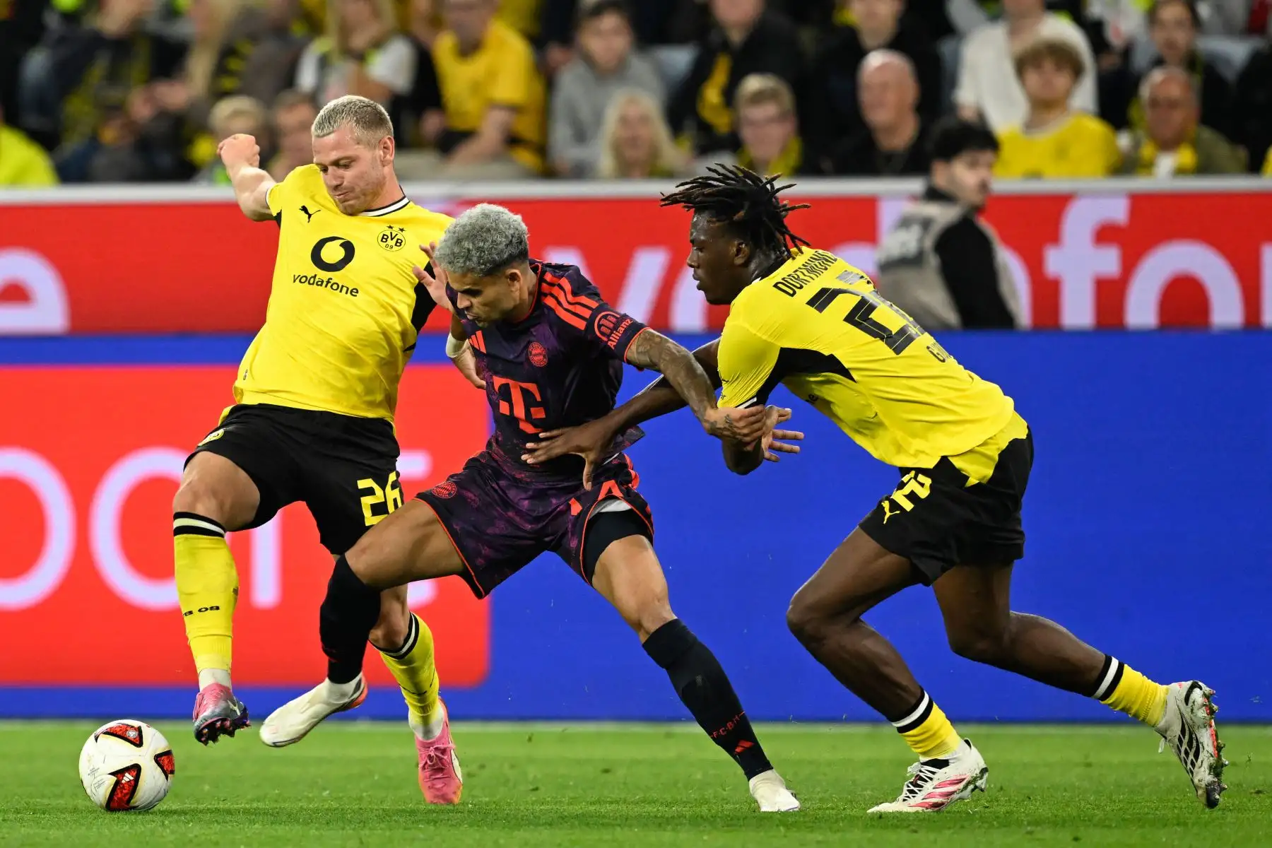 El defensa noruego del Dortmund, Julian Ryerson, el delantero colombiano del Bayern de Múnich, Luis Díaz, y el defensa francés del Dortmund, Joane Gadou, se enfrentan por el balón durante el partido de fútbol de la Supercopa Franz Beckenbauer entre el Borussia Dortmund y el FC Bayern de Múnich. Foto: AFP