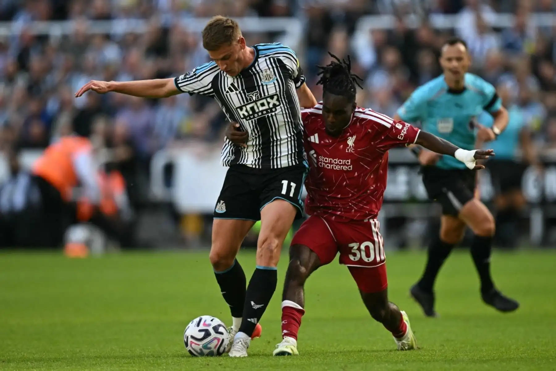 El defensa neerlandés del Liverpool, Jeremie Frimpong (n.º 30), es amonestado por esta falta sobre el centrocampista inglés del Newcastle United, Harvey Barnes (n.º 11), durante el partido de la Premier League inglesa entre el Newcastle United y el Liverpool en St James