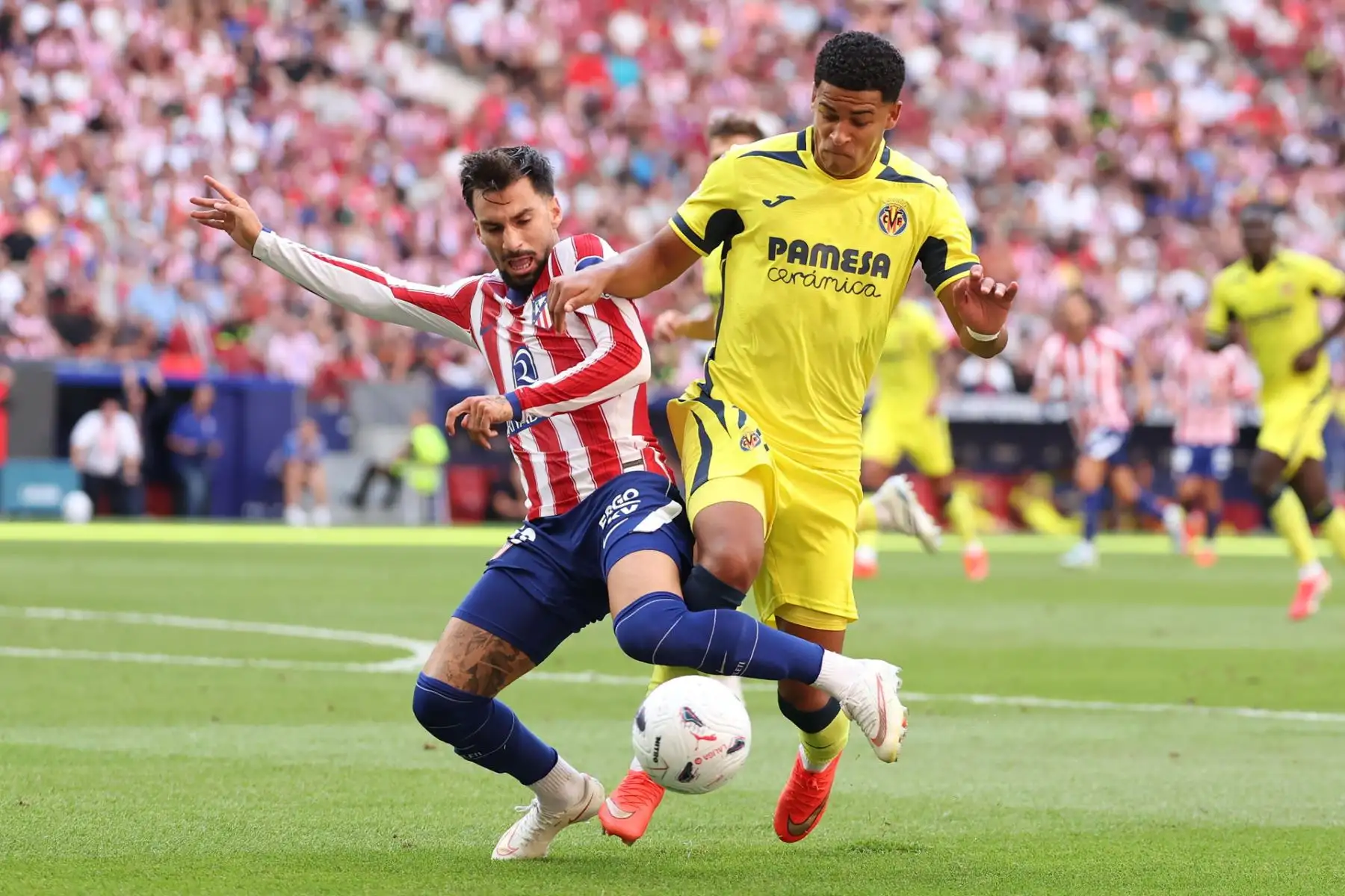 El centrocampista del Atlético de Madrid Álex Baena (i) pelea un balón con un jugador del Villarreal, durante el partido de LaLiga de fútbol que Atlético de Madrid y Villarreal CF disputan este domingo en el estadio Metropolitano.  Foto: EFE