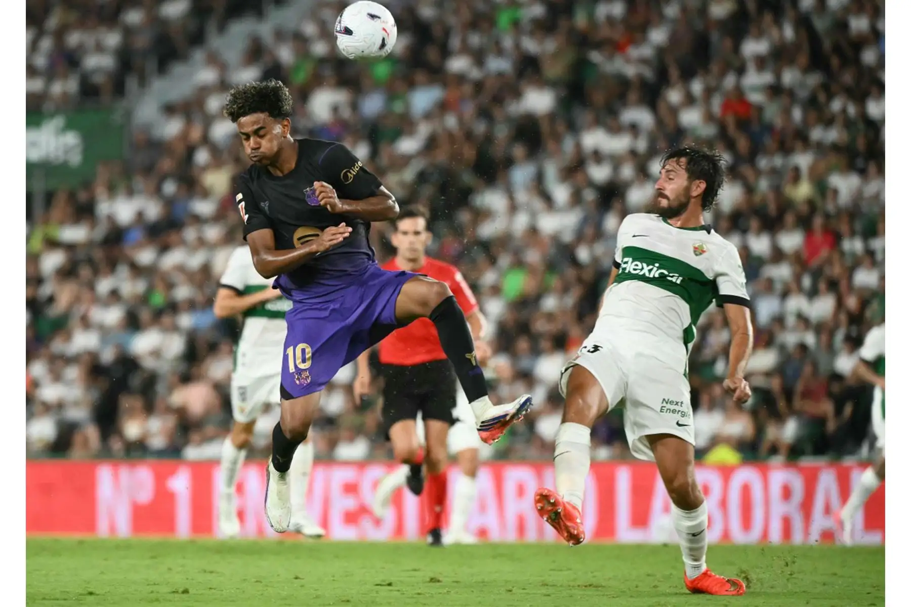 El delantero español del Barcelona, ​​Lamine Yamal, lucha por el balón con el defensa español del Elche, Víctor Chust, durante el partido de la liga española de fútbol entre el Elche CF y el FC Barcelona en el estadio Martínez Valero de Elche, el 23 de agosto de 2026. Foto: AFP