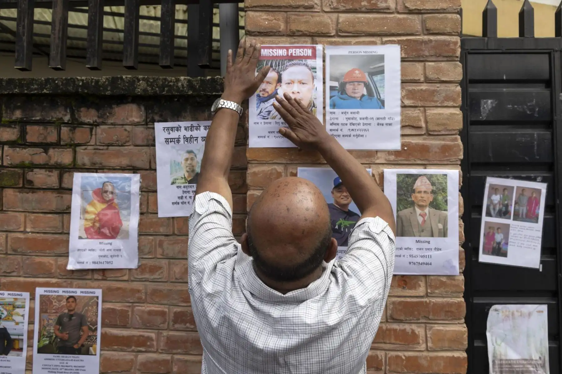 Un hombre coloca un cartel con fotos de personas desaparecidas tras la riada a lo largo de la frontera entre Nepal y el Tíbet en una pared del Hospital Universitario de Tribhuvan (TUTH), en Katmandú. Foto: EFE