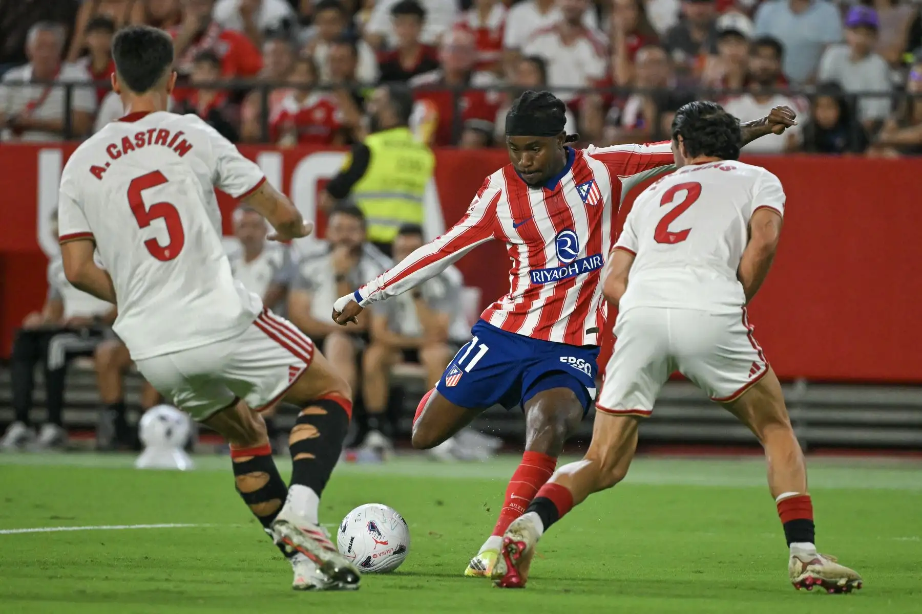 El delantero nigeriano del Atlético de Madrid, Ademola Lookman, dispara entre los defensas españoles del Sevilla, Andrés Castrín y Juan Iglesias, para marcar un gol durante el partido de la liga española de fútbol entre el Sevilla FC y el Club Atlético de Madrid, disputado en el estadio Ramón Sánchez-Pizjuán de Sevilla el 29 de agosto de 2026. Foto: AFP