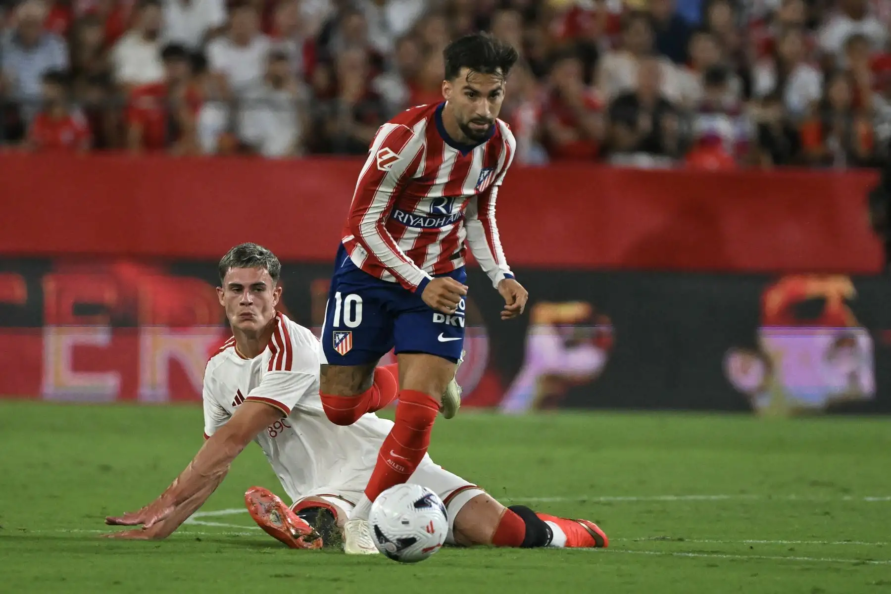 El delantero español del Atlético de Madrid, Alex Baena, conduce el balón ante el delantero escocés del Sevilla, Robbie Ure, durante el partido de la liga española de fútbol entre el Sevilla FC y el Club Atlético de Madrid en el estadio Ramón Sánchez-Pizjuán de Sevilla, el 29 de agosto de 2026. Foto: AFP