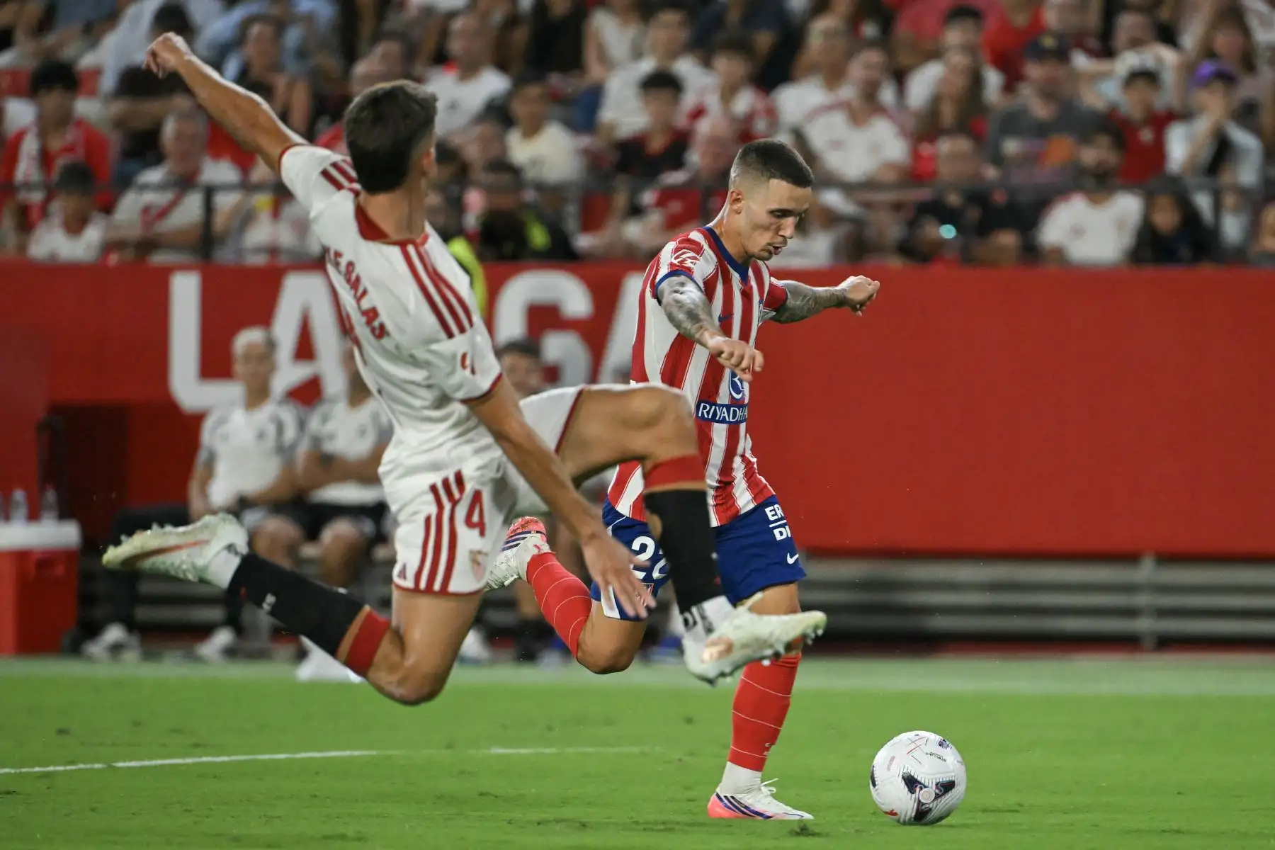 El defensa español del Atlético de Madrid, Alejandro Grimaldo, disputa el balón con el defensa español del Sevilla, Kike Salas, durante el partido de la liga española de fútbol entre el Sevilla FC y el Club Atlético de Madrid en el estadio Ramón Sánchez-Pizjuán de Sevilla, el 29 de agosto de 2026. Foto: AFP
