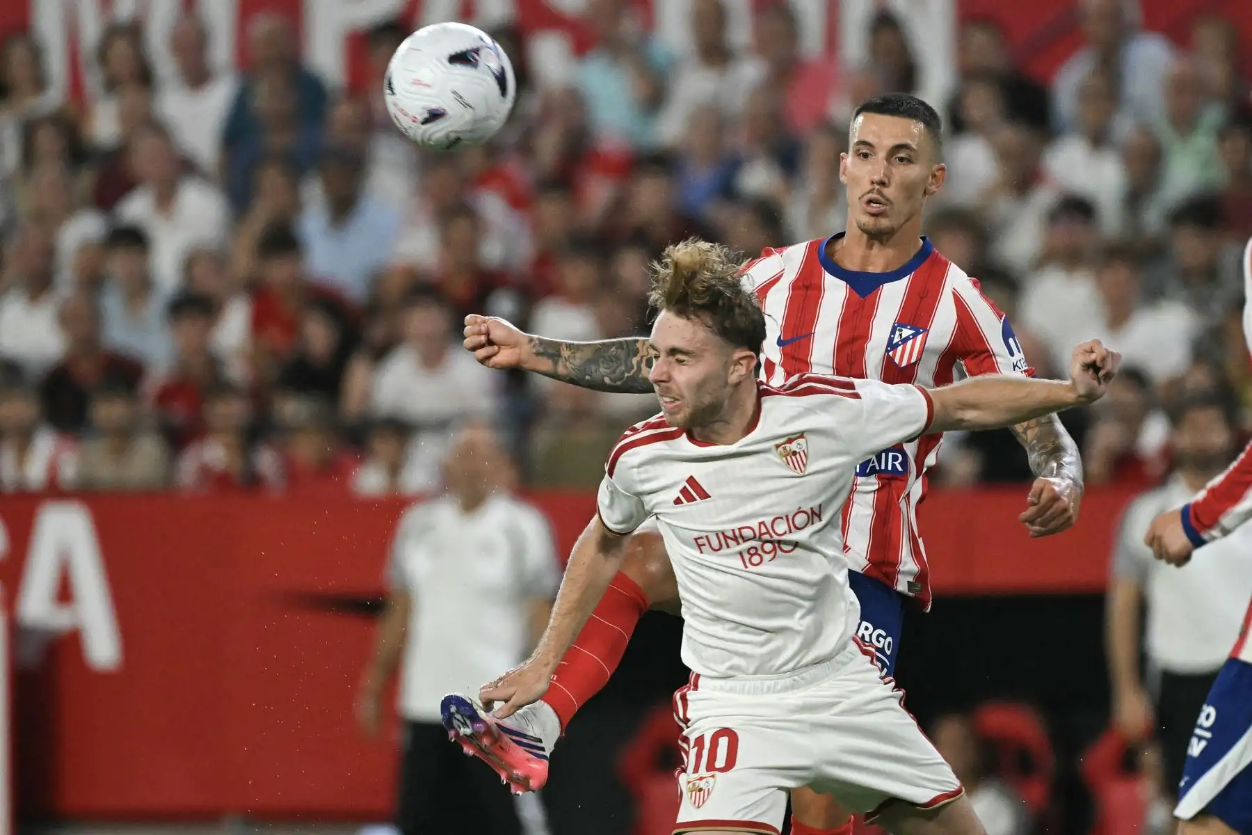 El delantero español del Sevilla, Gerard Peque, disputa el balón con el defensa español del Atlético de Madrid, Alejandro Grimaldo, durante el partido de la liga española de fútbol entre el Sevilla FC y el Club Atlético de Madrid en el estadio Ramón Sánchez-Pizjuán de Sevilla, el 29 de agosto de 2026. Foto: AFP