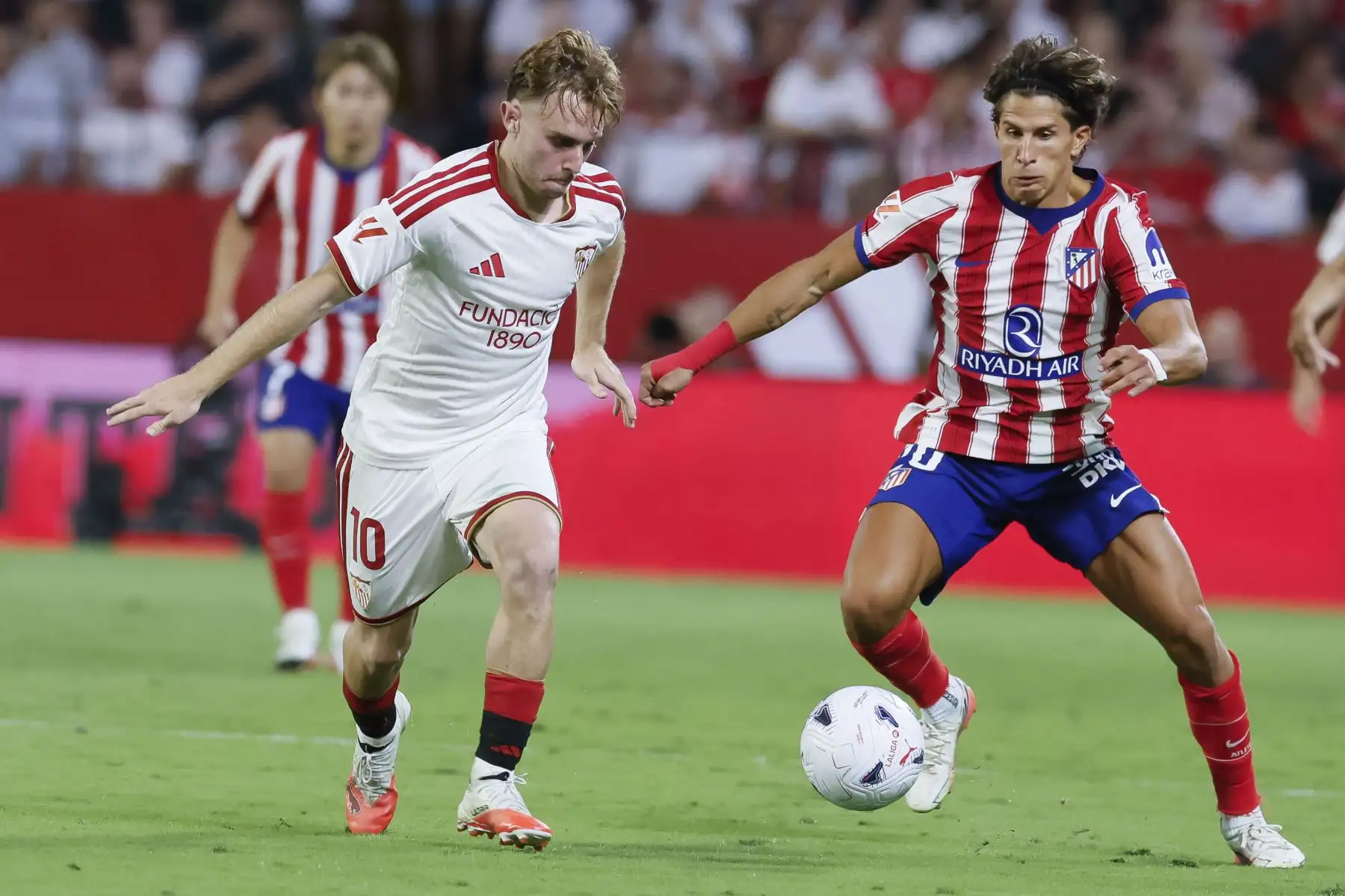 El delantero del Atlético de Madrid, Giuliano Simeone, lucha con Peque del Sevilla, durante el partido de la tercera jornada de LaLiga entre Sevilla FC y Atlético de Madrid hoy sábado 29 de agosto en el estadio Sánchez-Pizjuán, en Sevilla. Foto: EFE